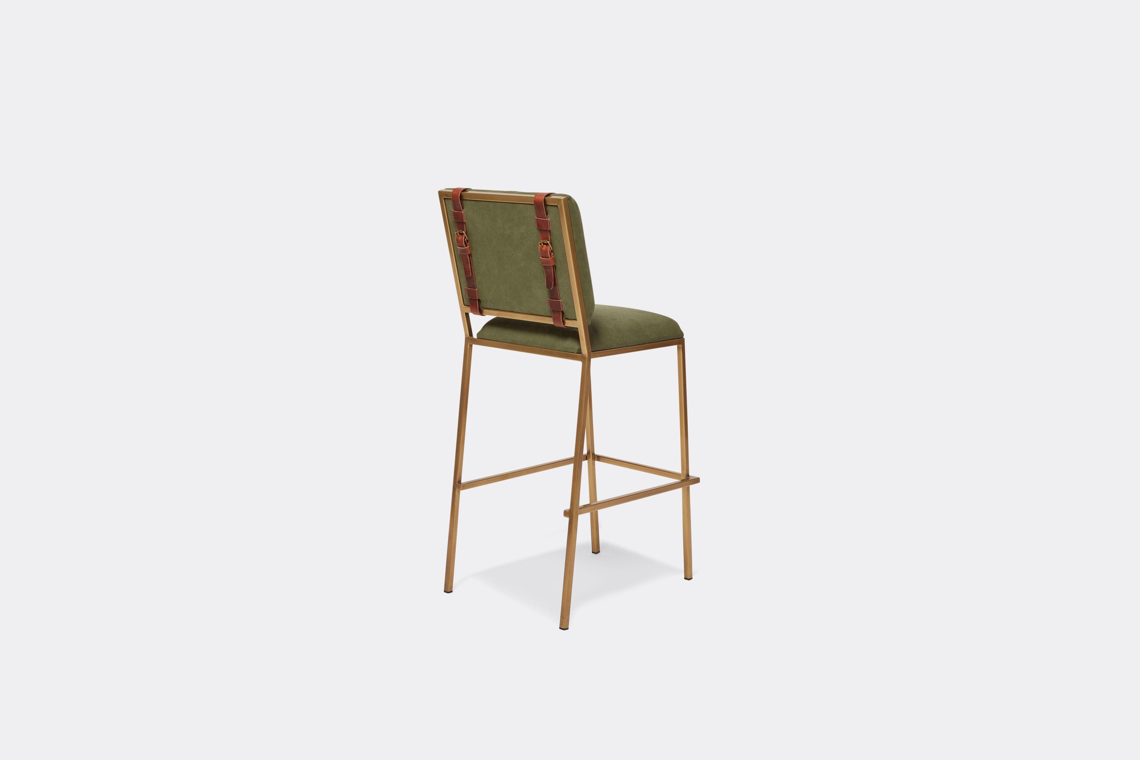 Sideview of barstool with military canvas upholstery and brown leather belts on antique brass metal legs