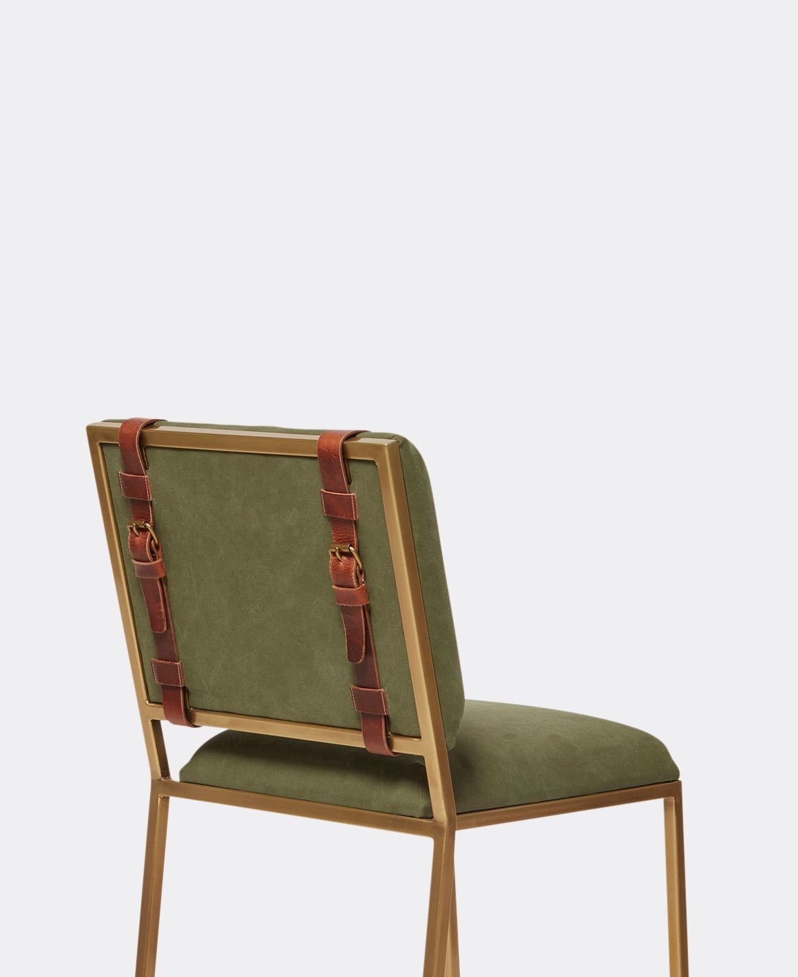 A green canvas upholstered bar stool with a brass finished steel frame and leather belts shown on a white background .