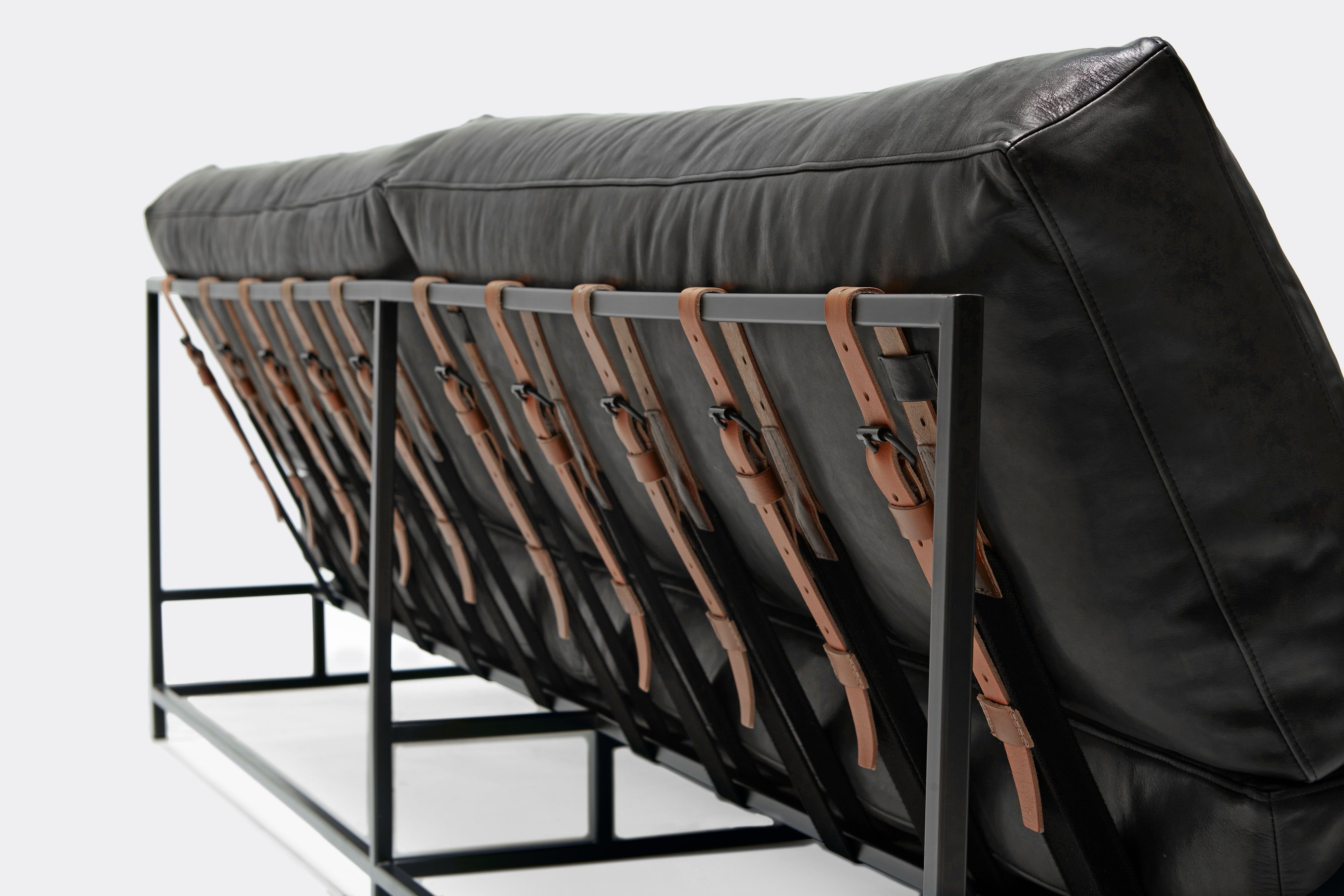 detail of loveseat with black leather upholstery on black metal frame