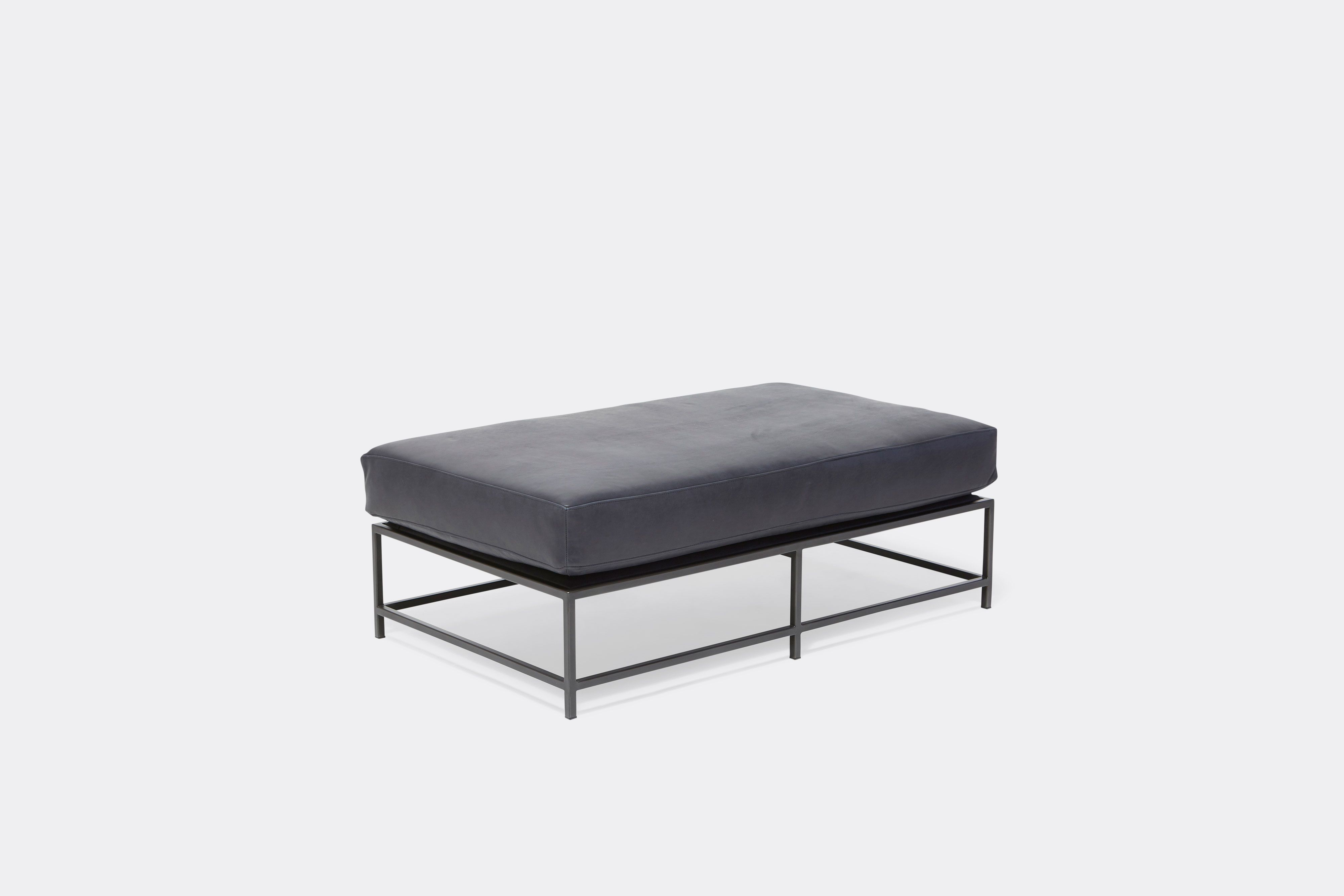 side of bench with blue leather upholstery on black metal frame