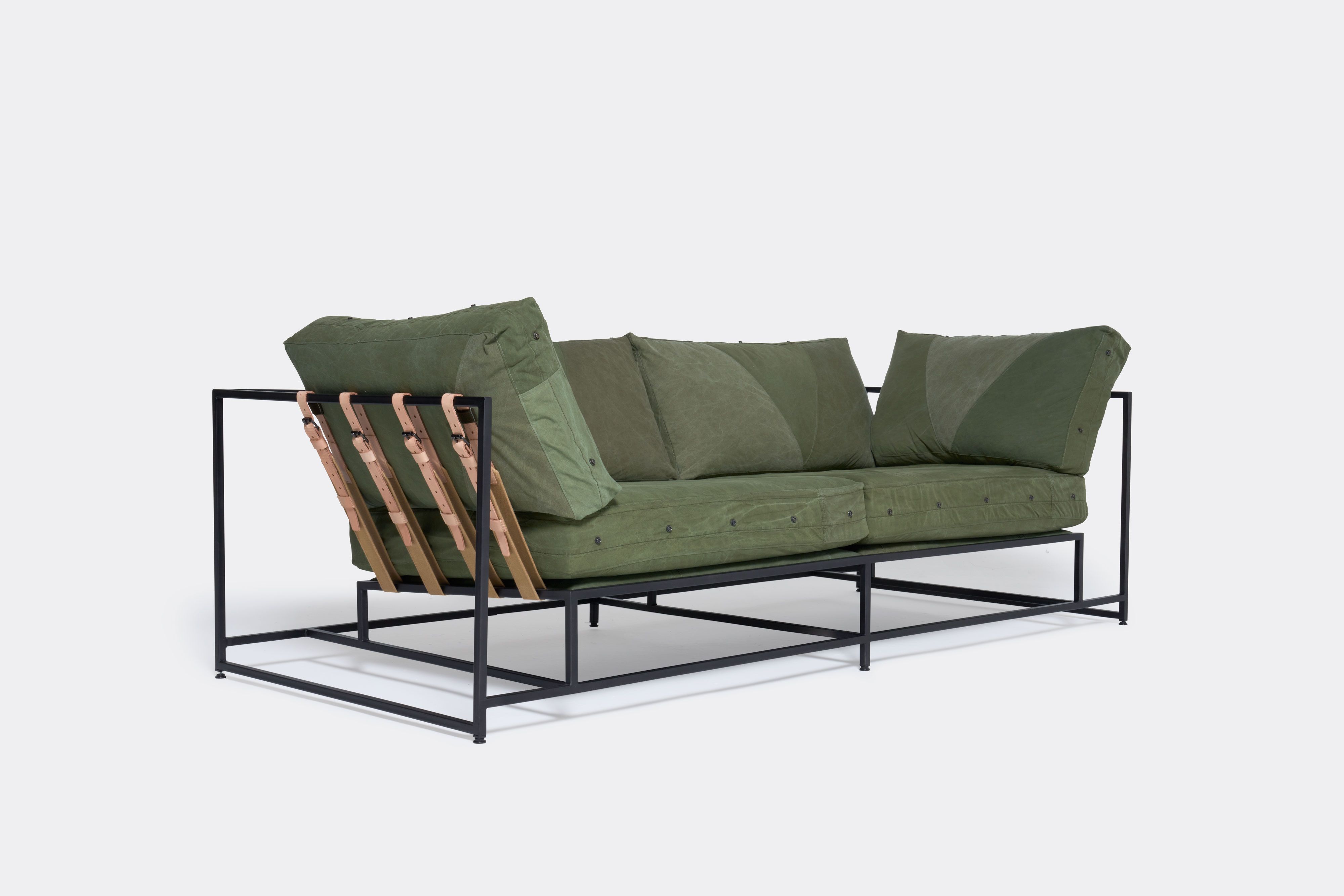 a green sofa with a black steel frame and green cushions on a white background .