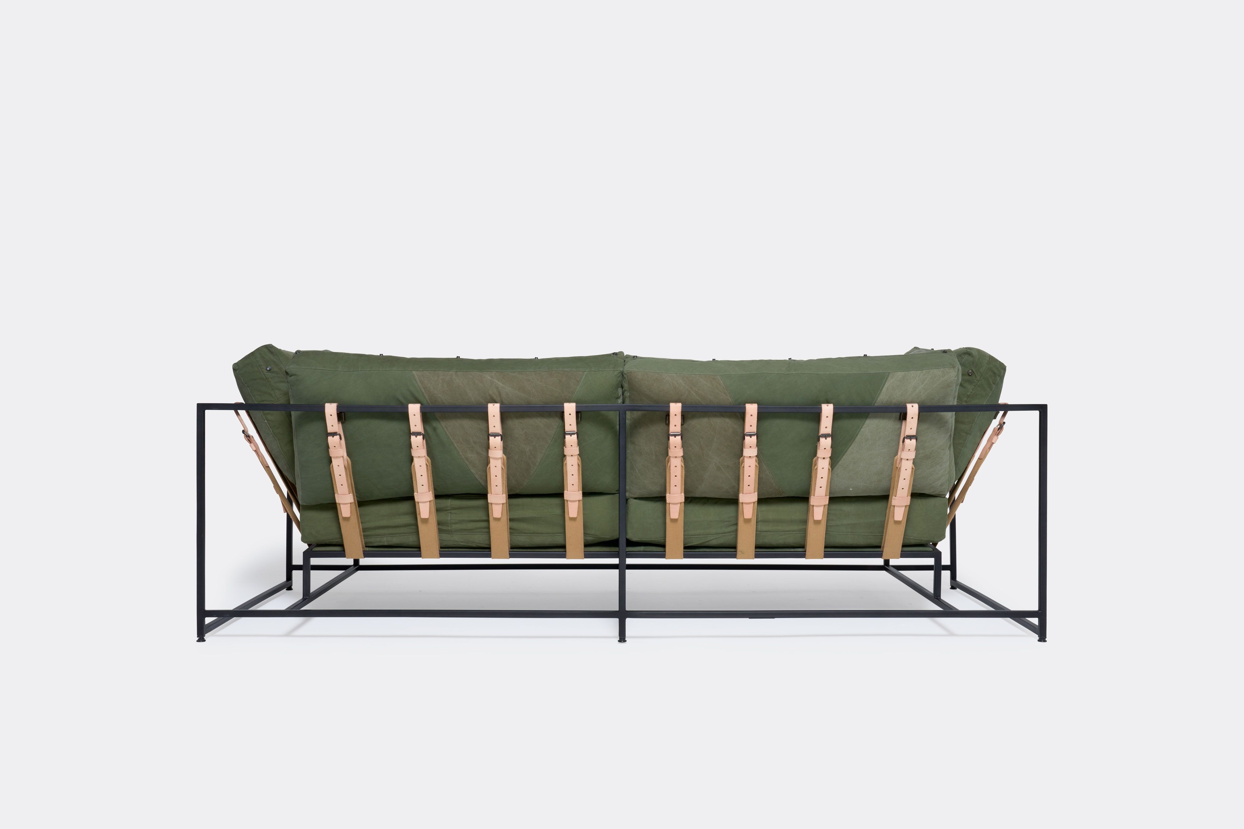 a green sofa with a black steel frame and green cushions on a white background .