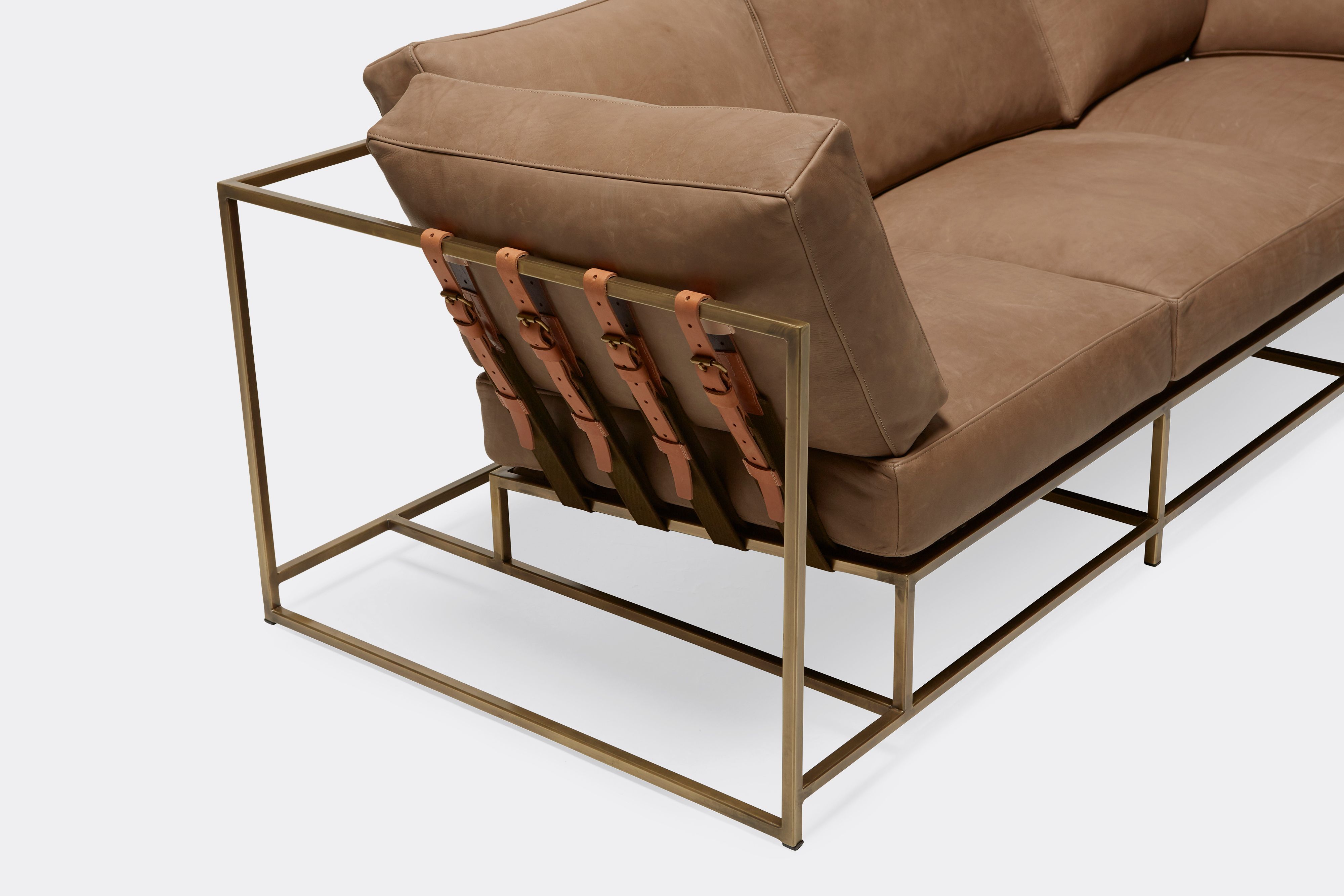 overhead view of Sofa with brown leather upholstery and brown leather belts on antique brass metal frame