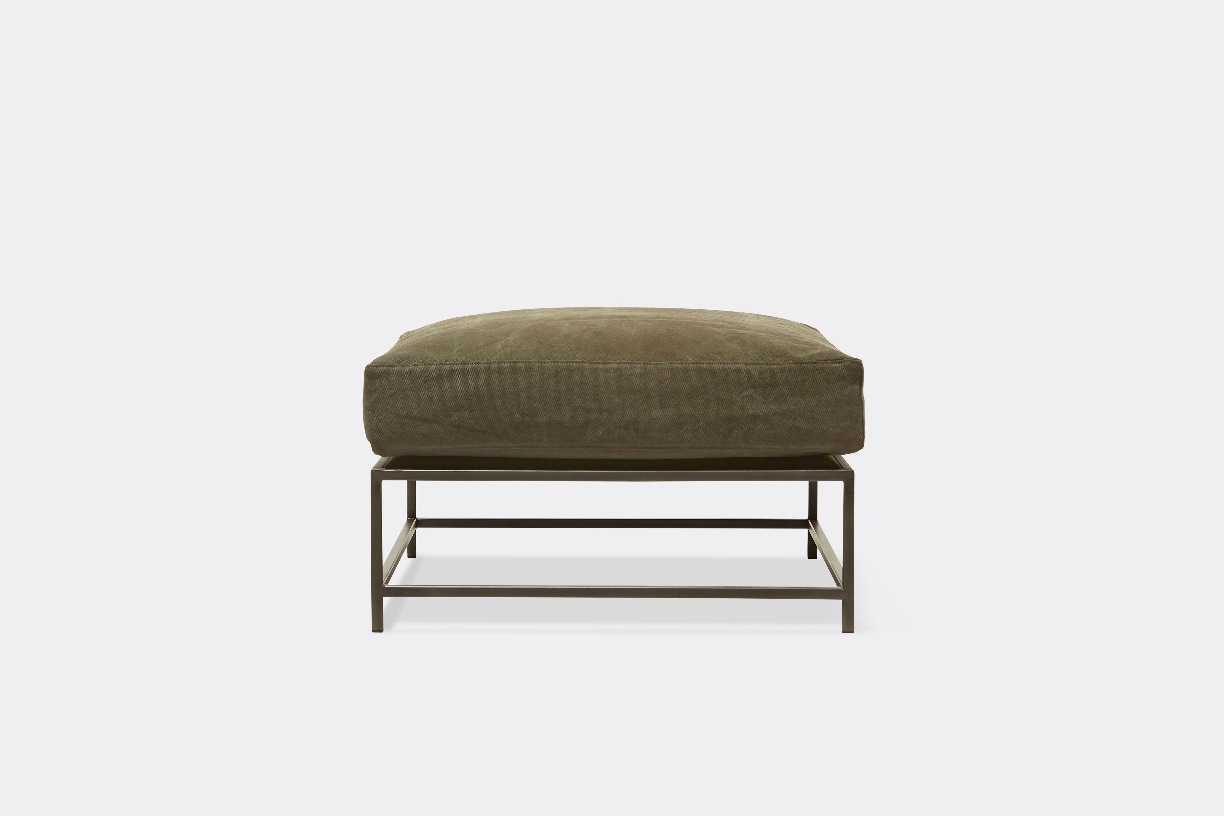 front view of green canvas ottoman with blackened steel frame