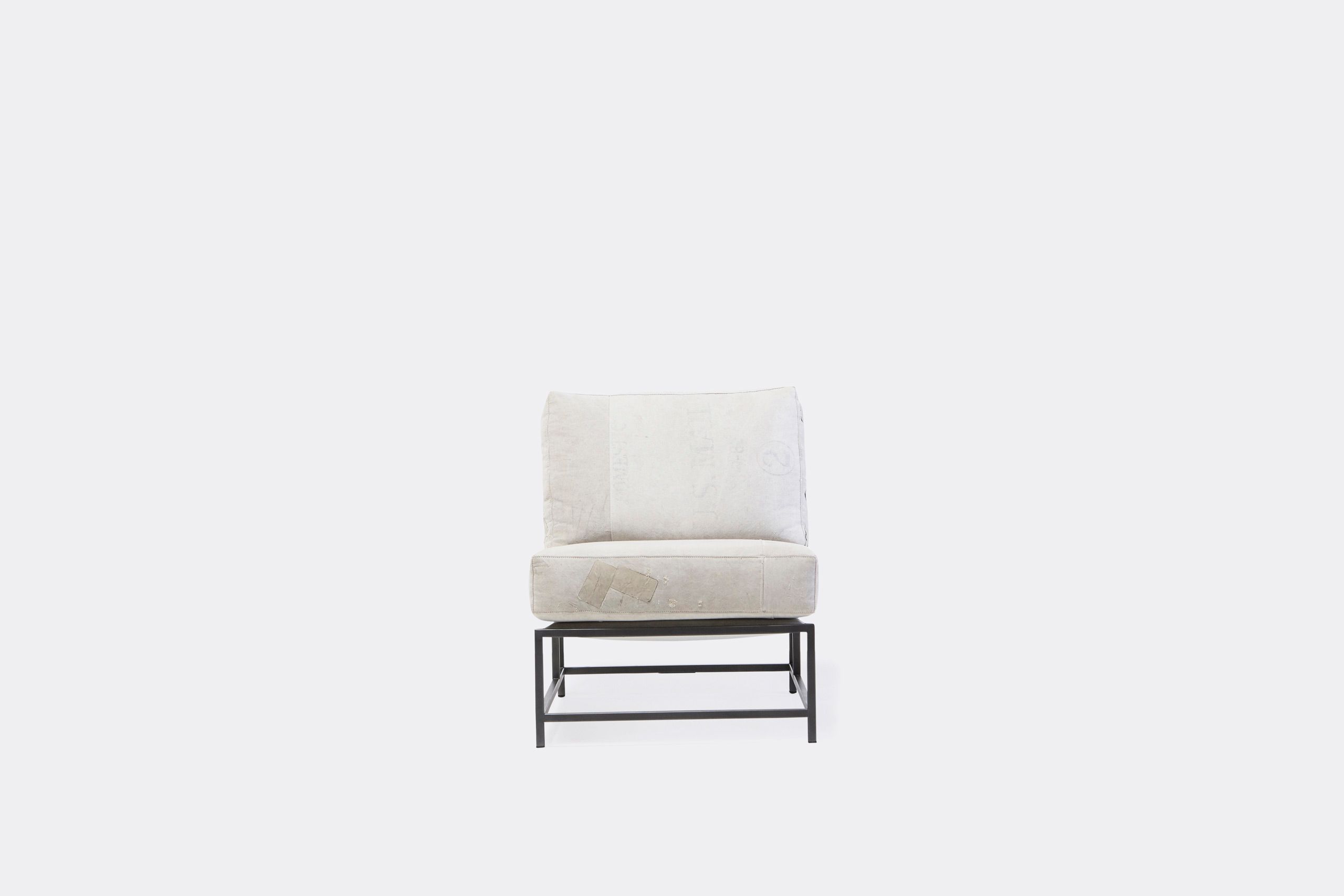 A chair with a white cushion and leather straps atop a blackened steel frame on a white background
