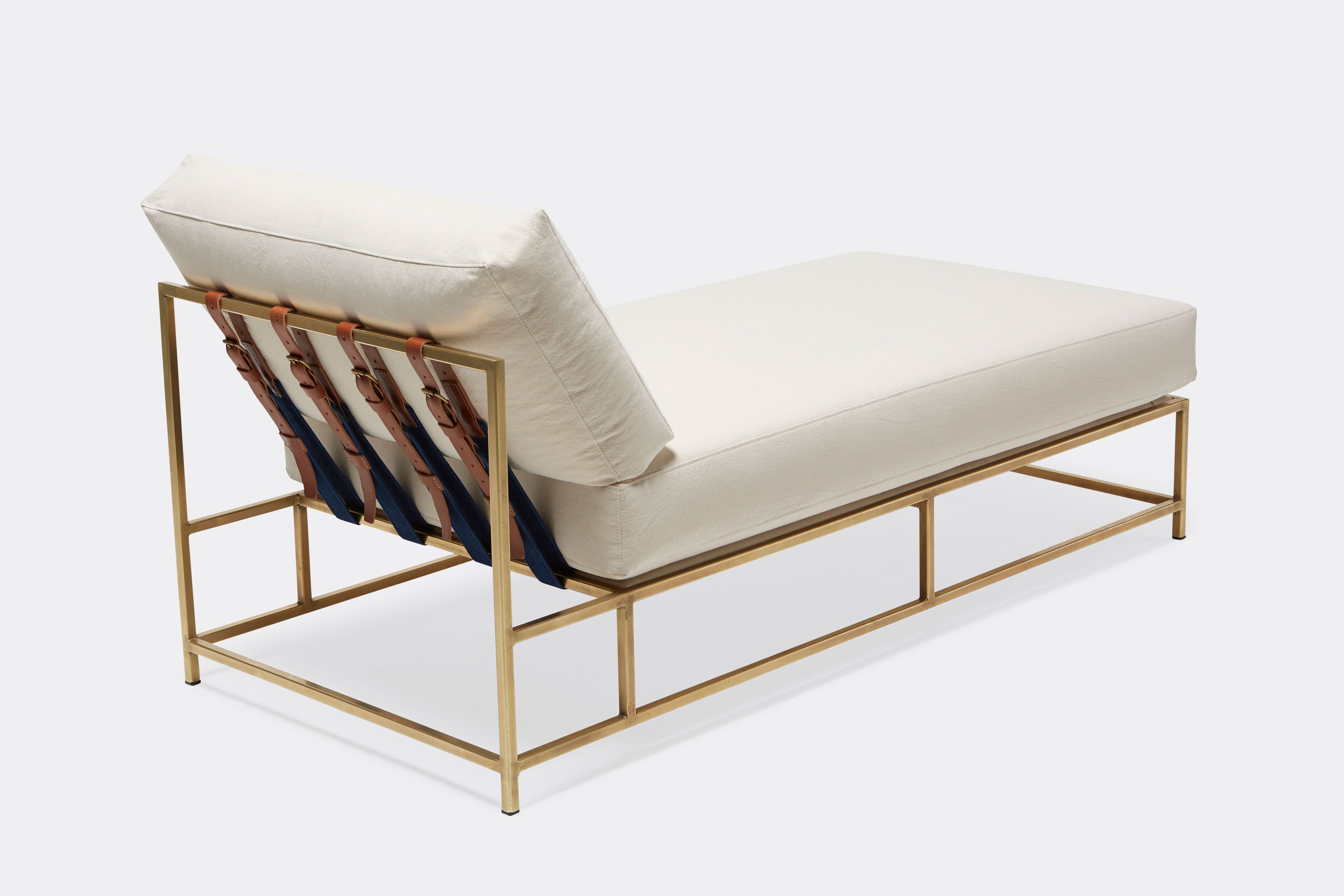 Sideview of lounge chaise with natural canvas upholstery and brown leather belt on tarnished brass metal frame