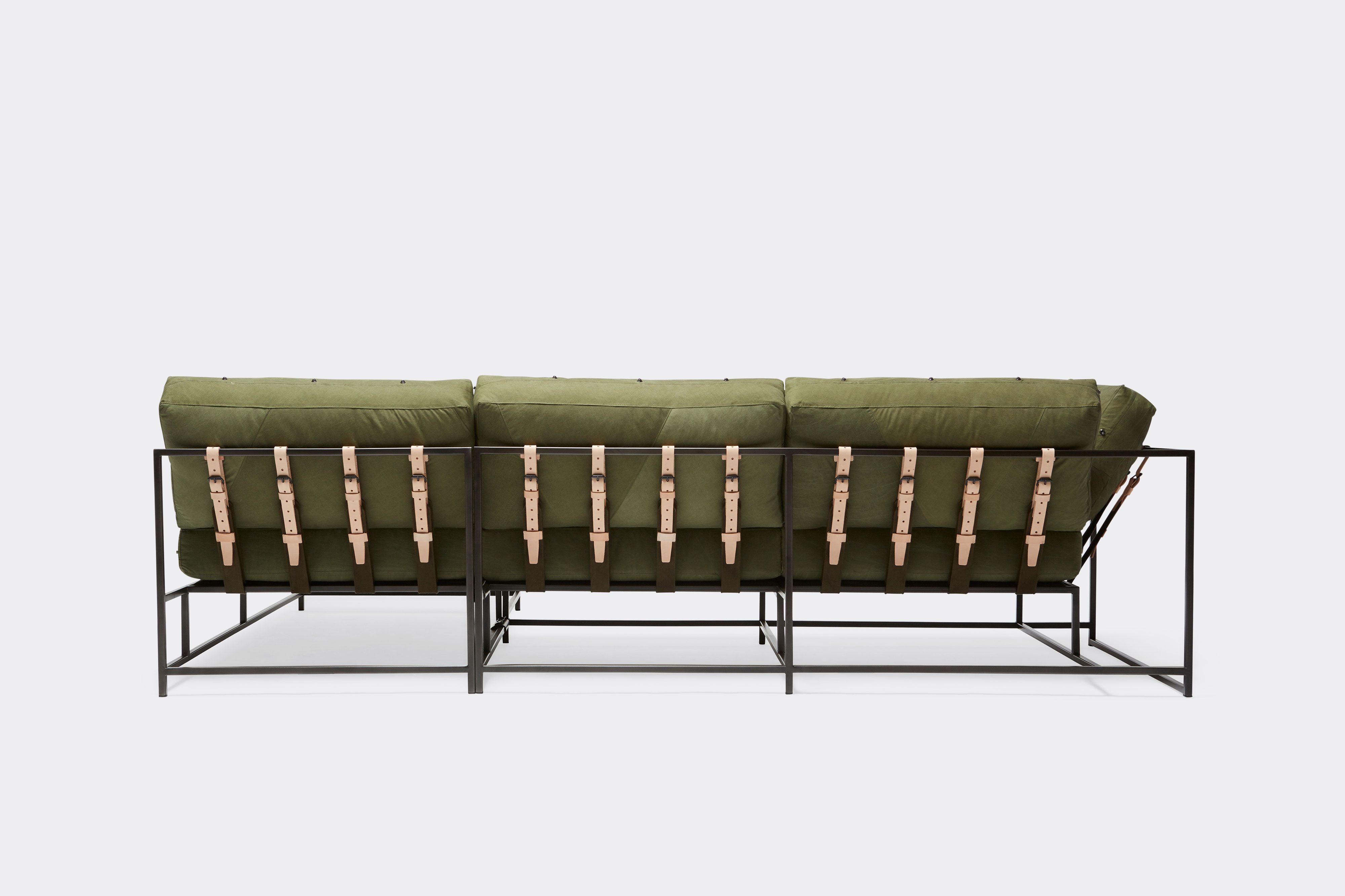 back of sectional with green canvas upholstery and natural tan leather belts on black metal frame