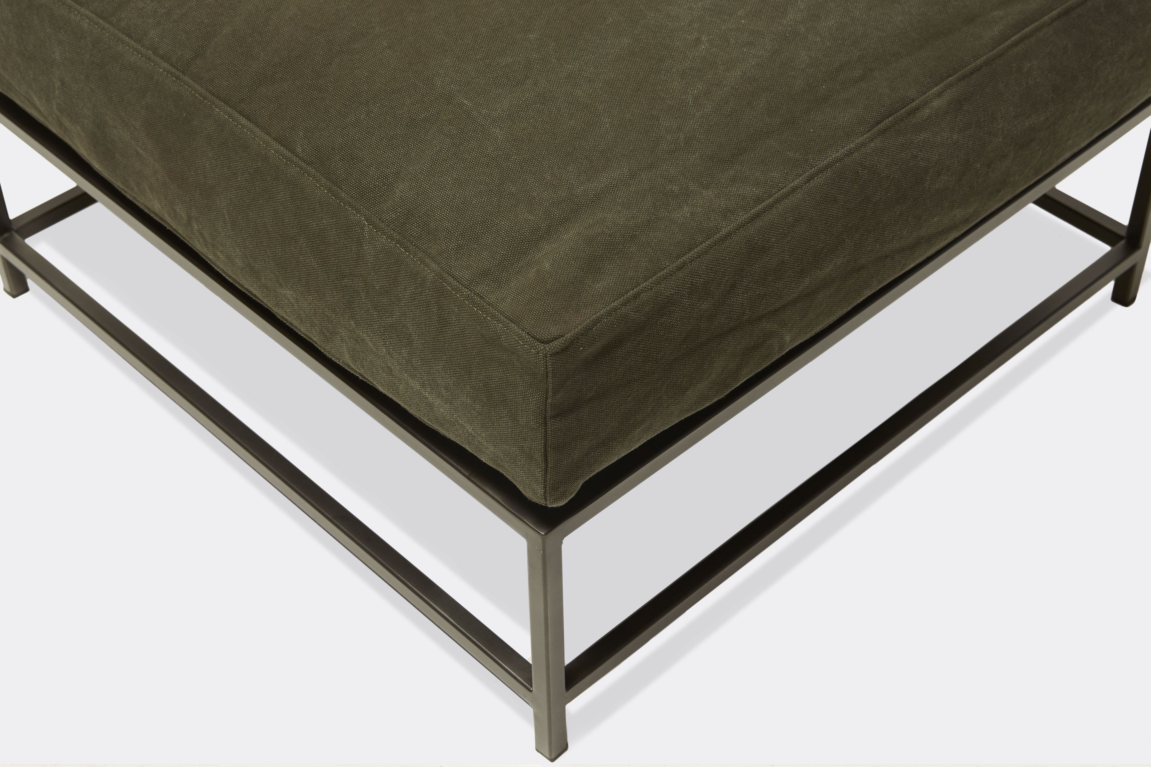 up close view of green canvas ottoman with blackened steel frame