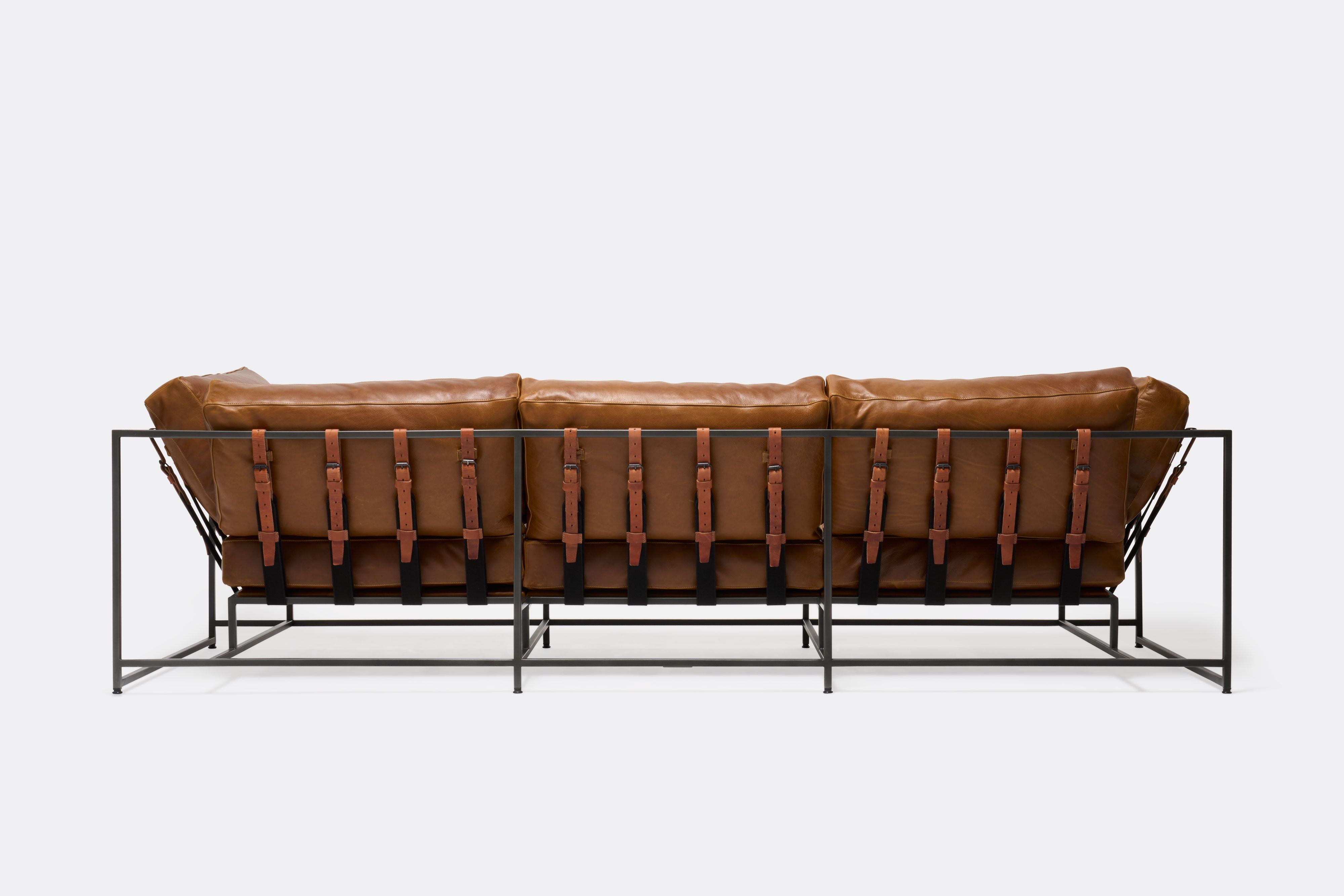 Back of Sofa with brown leather upholstery and brown leather belts on black metal frame