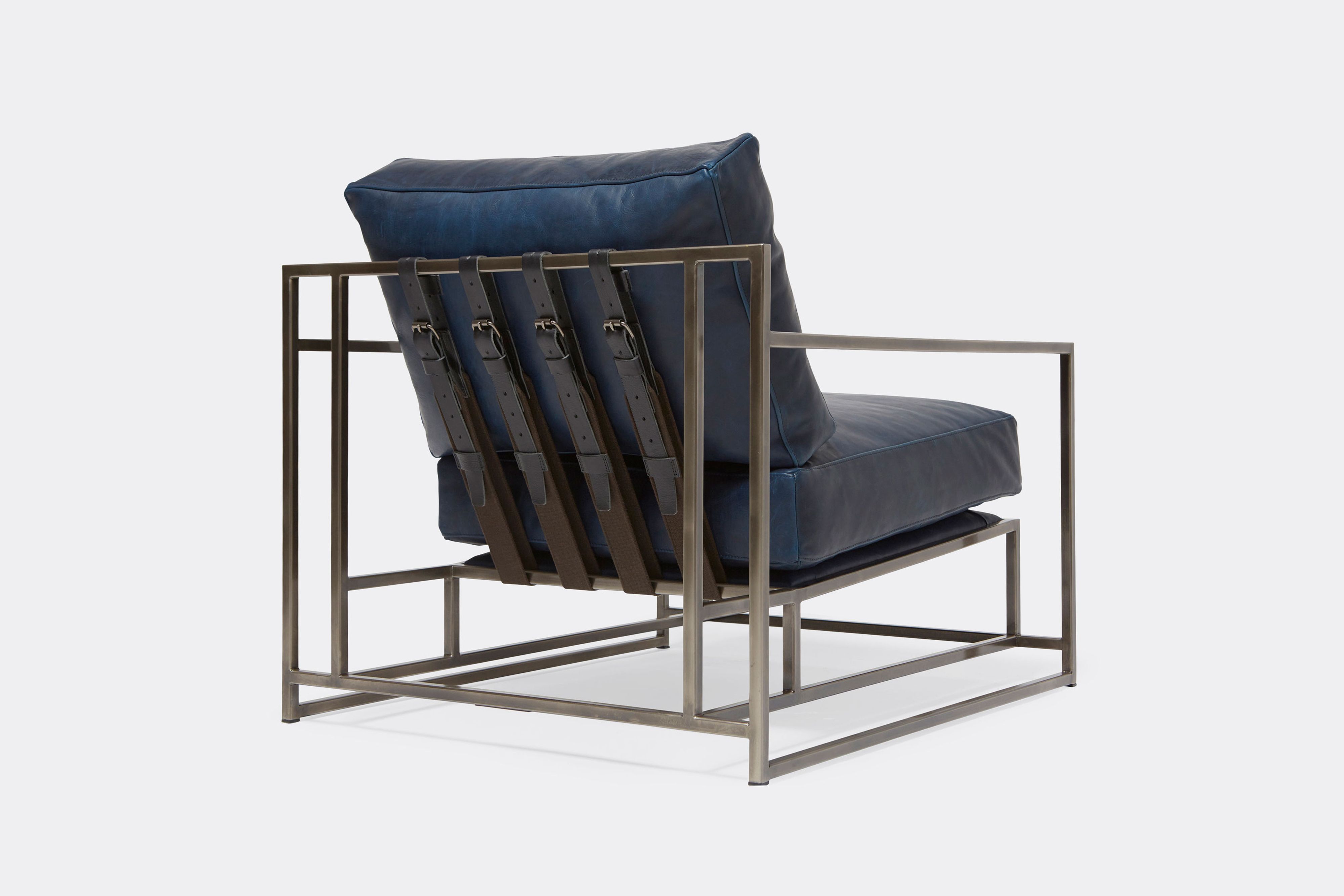 a navy blue leather armchair with a black steel frame and black supporting belts shown on a white background .