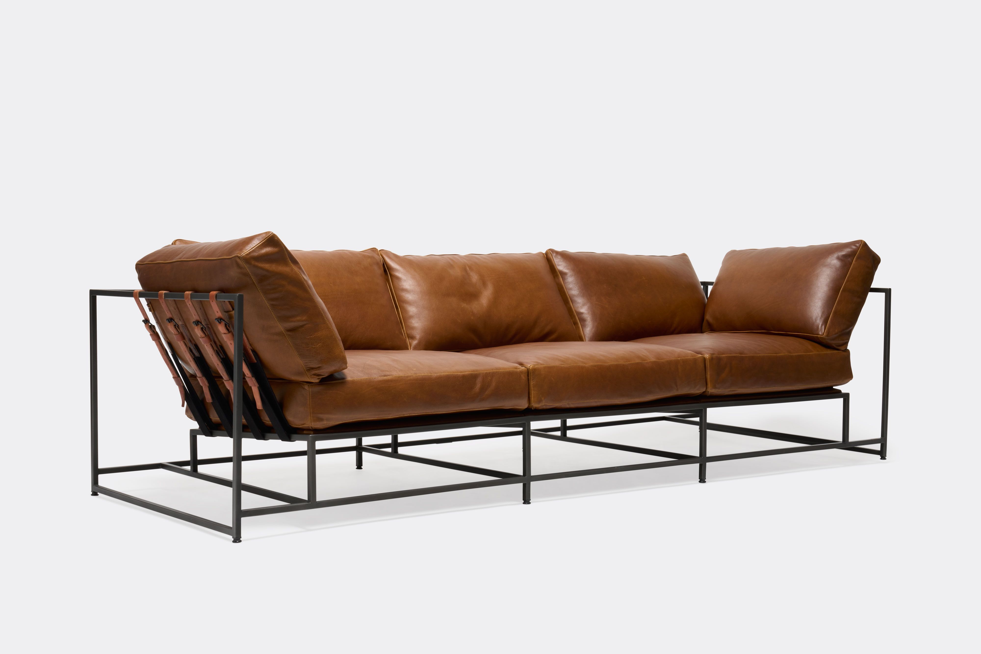 side of Sofa with brown leather upholstery and brown leather belts on black metal frame