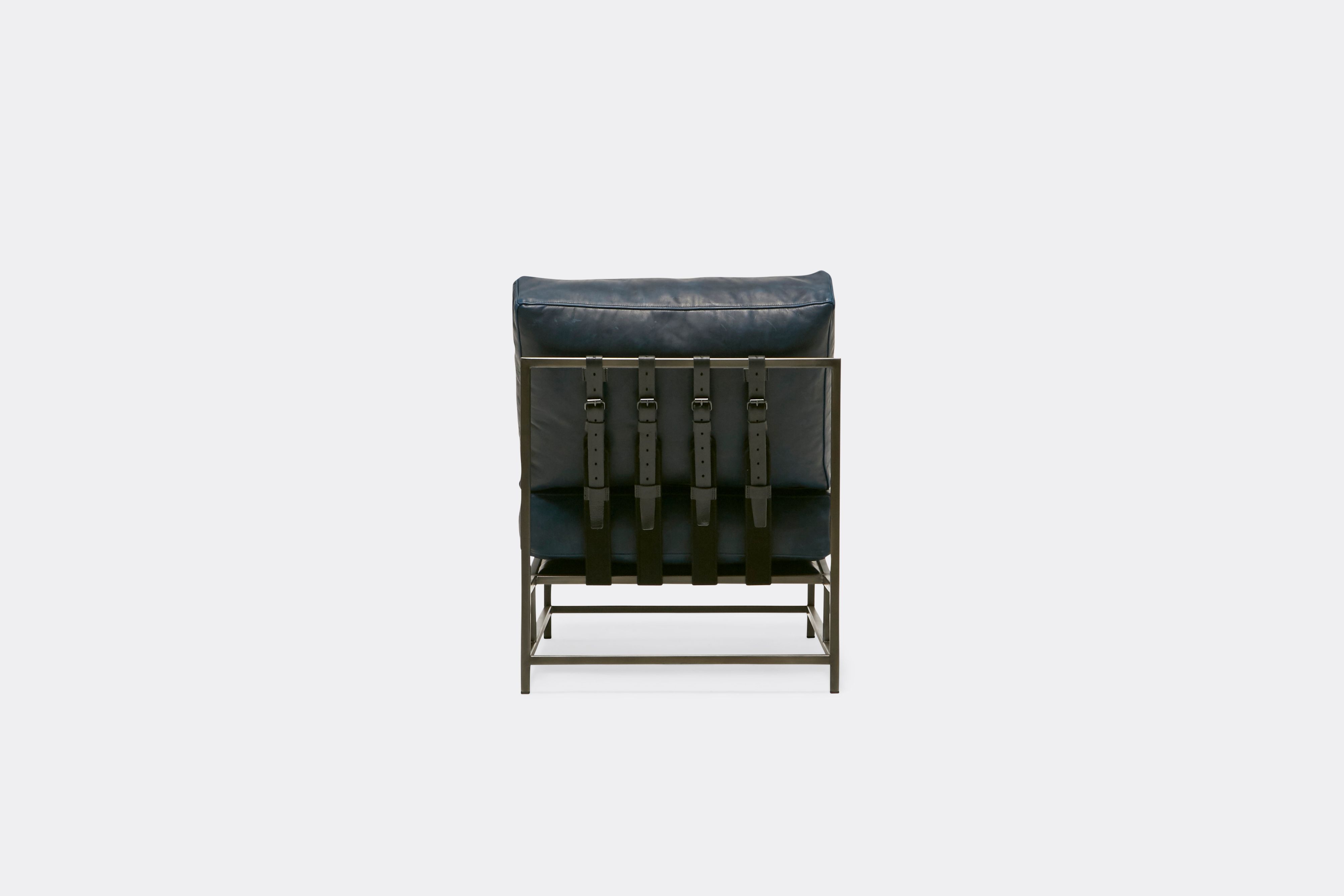 back of lounge chair  with blue leather upholstery and black leather belts on antique nickel metal frame