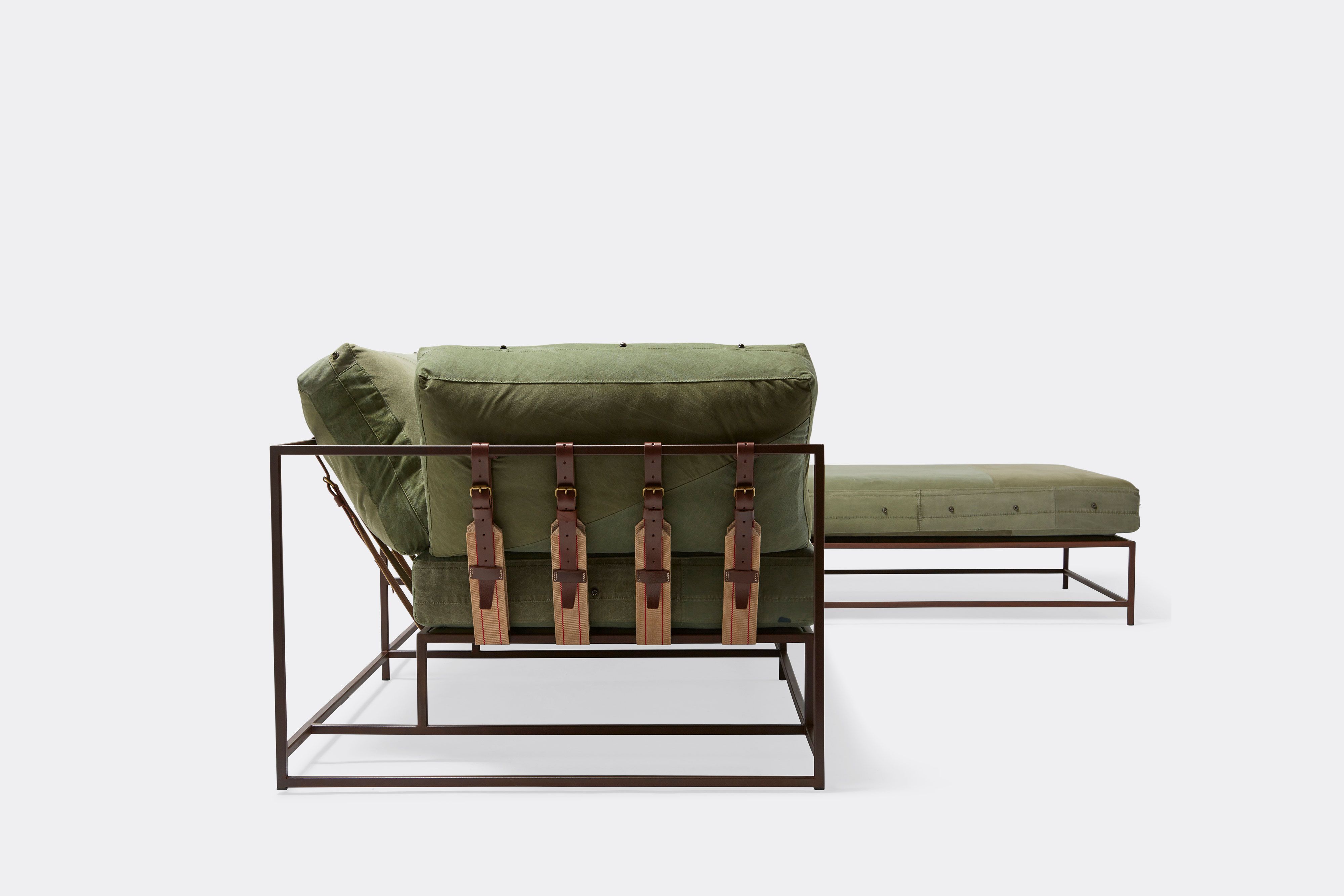 a green canvas sectional sofa with a steel frame and supporting belts shown on a white background .