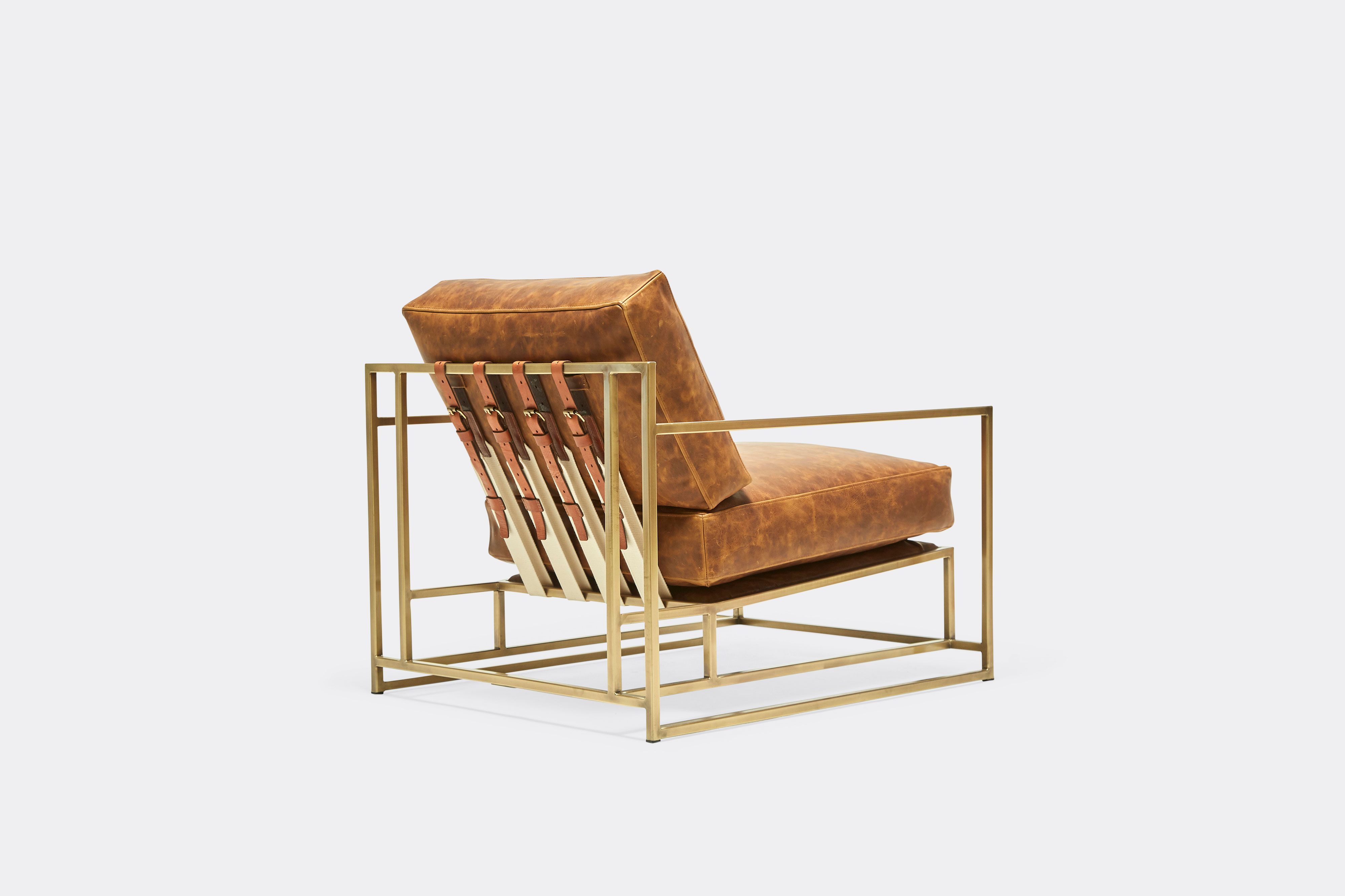 back of armchair with brown leather upholstery and brown leather belts on antique brass metal frame