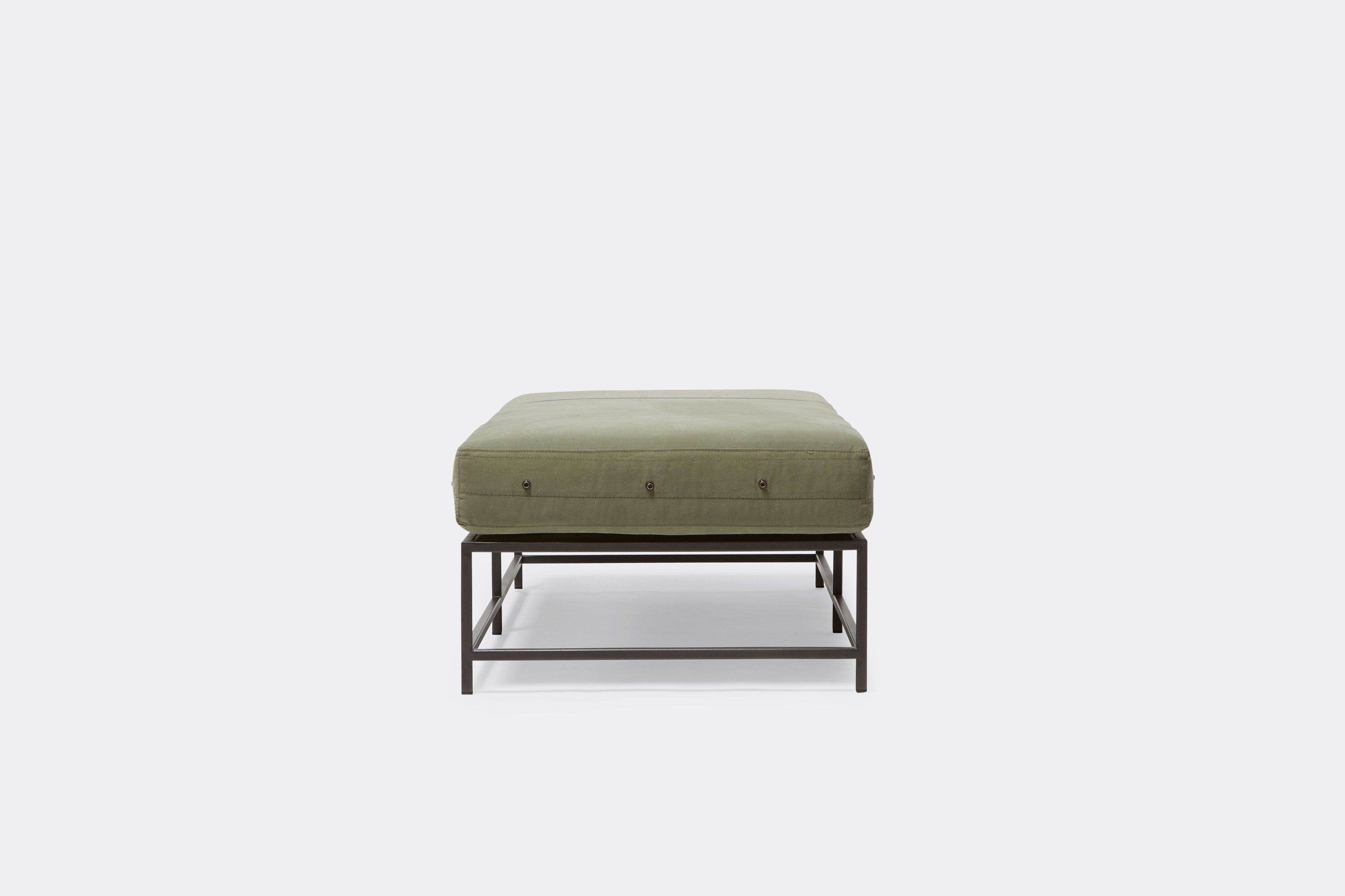 side of bench with green canvas upholstery on black metal frame