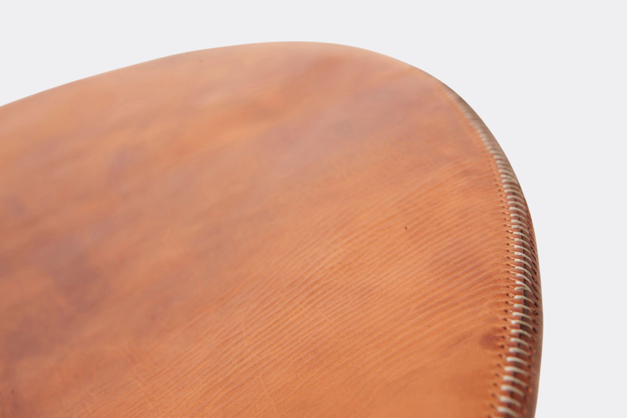 a brown leather chaise lounge with a steel frame and stone base shown on a white background .