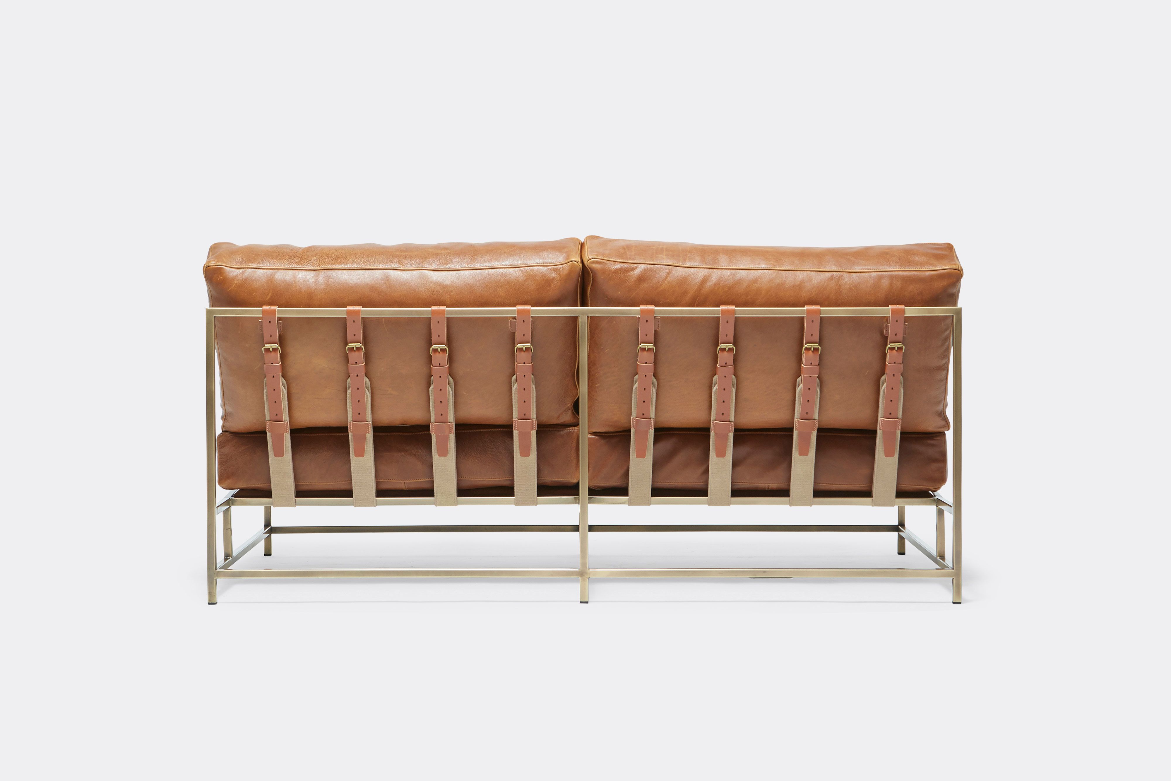 back of loveseat with brown leather upholstery and brown leather belts on antique brass metal frame