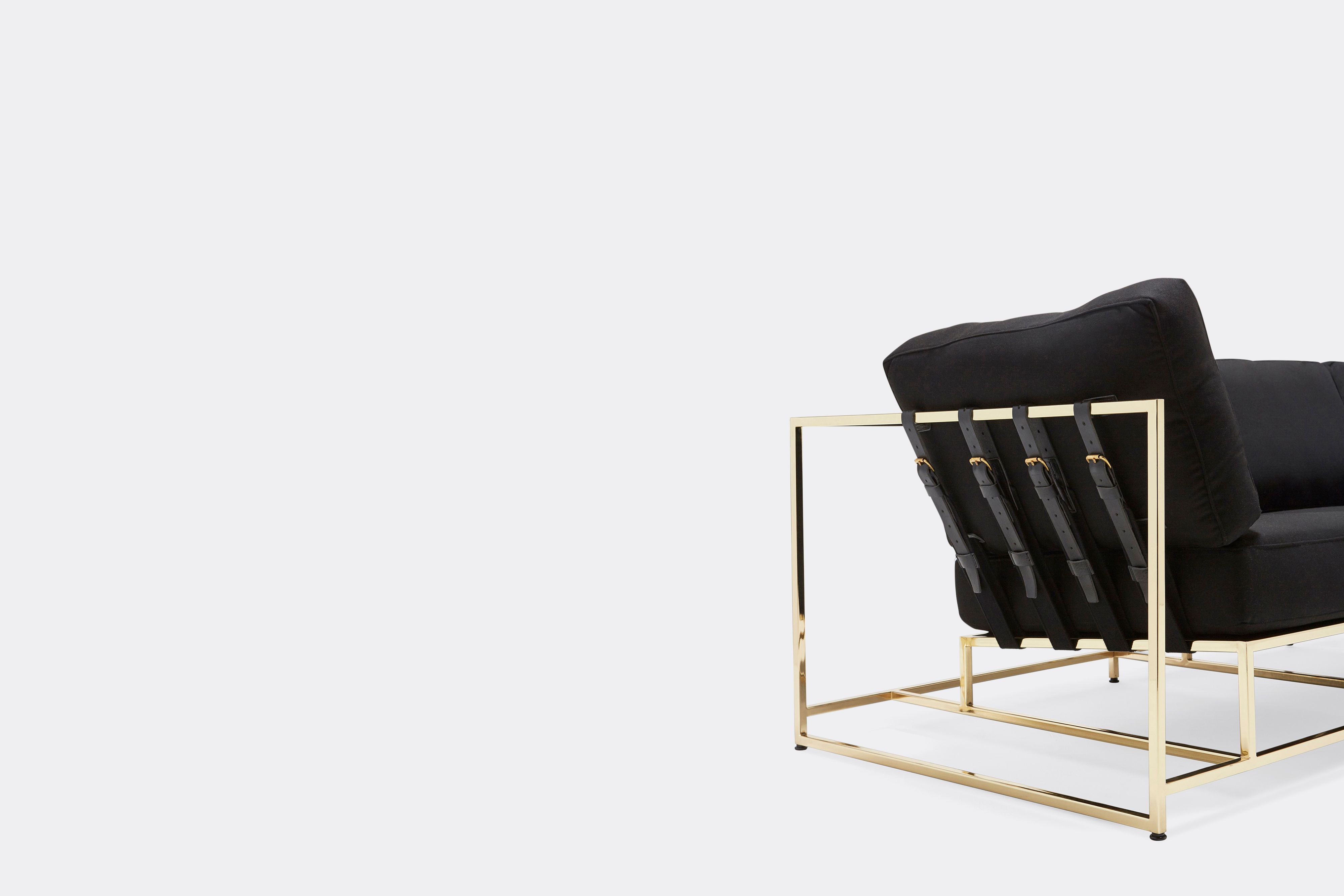 a black wool upholstered sofa with a polished brass finished steel frame on a and black supporting belts shown on a white background