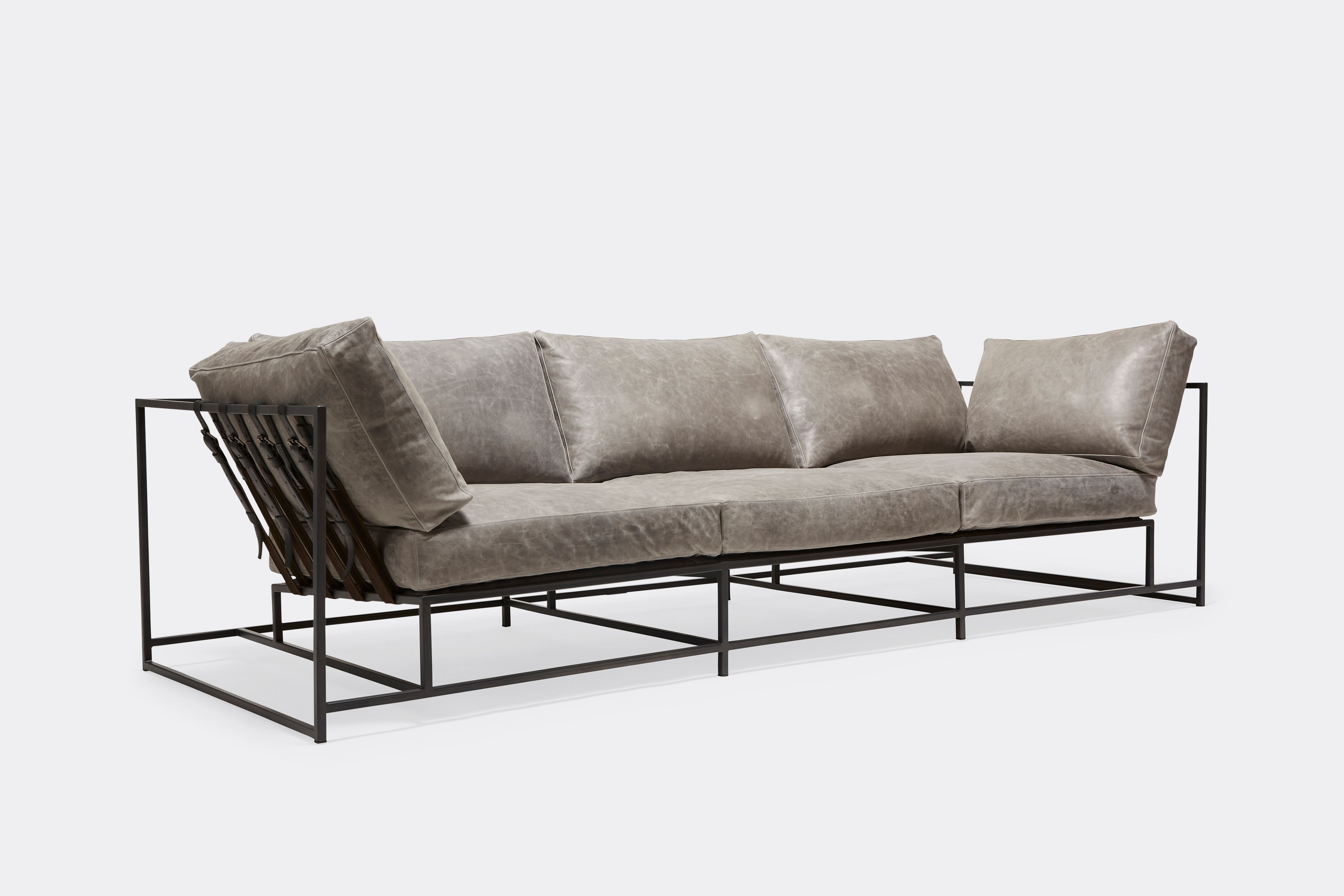 sideview of Sofa with gray leather upholstery and black leather belts on gray powdercoat metal frame