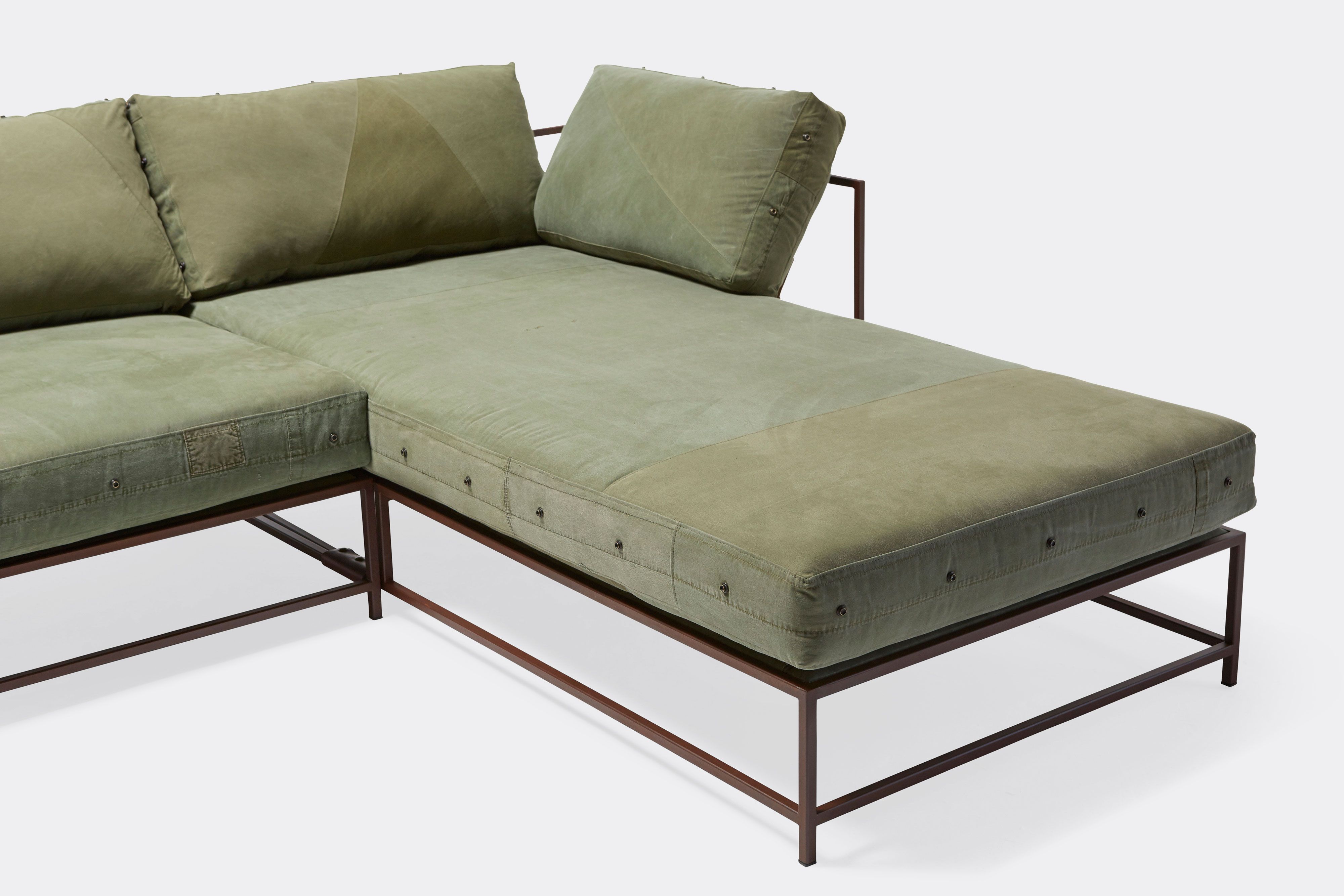 detail of sectional with green canvas upholstery on marble rust metal frame