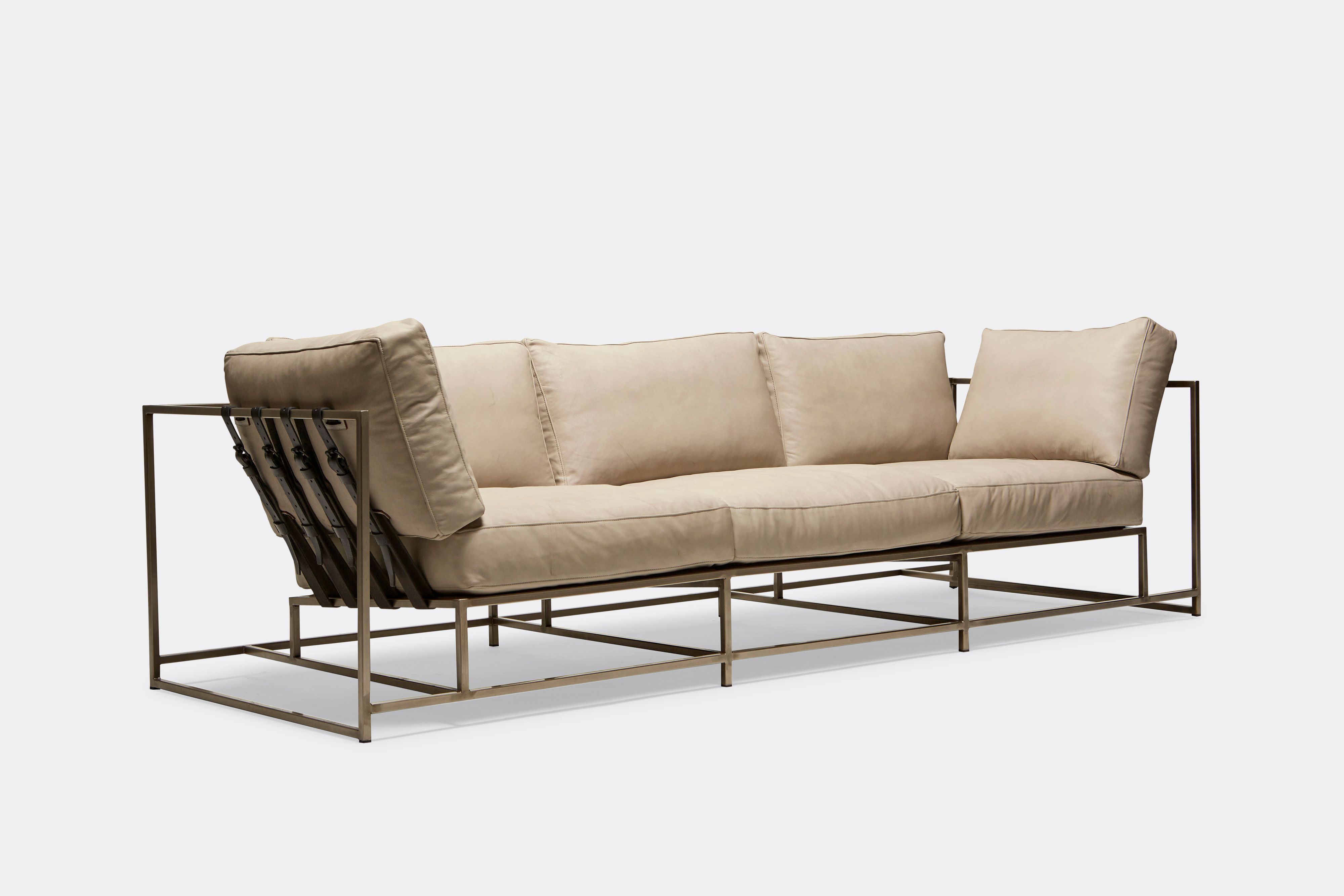 Sideview of Sofa with cream leather upholstery and black leather belts on antique nickel metal frame