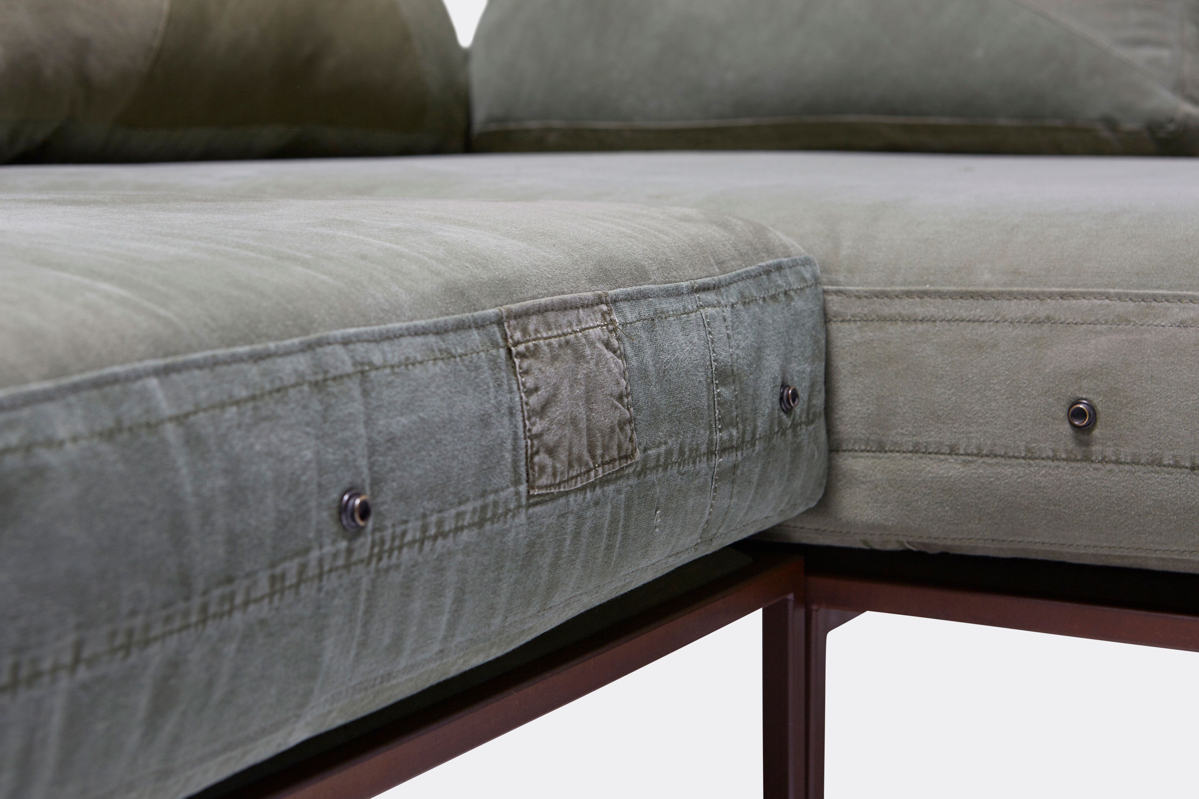 a close up of a green canvas sofa with a steel frame shown on a white background .