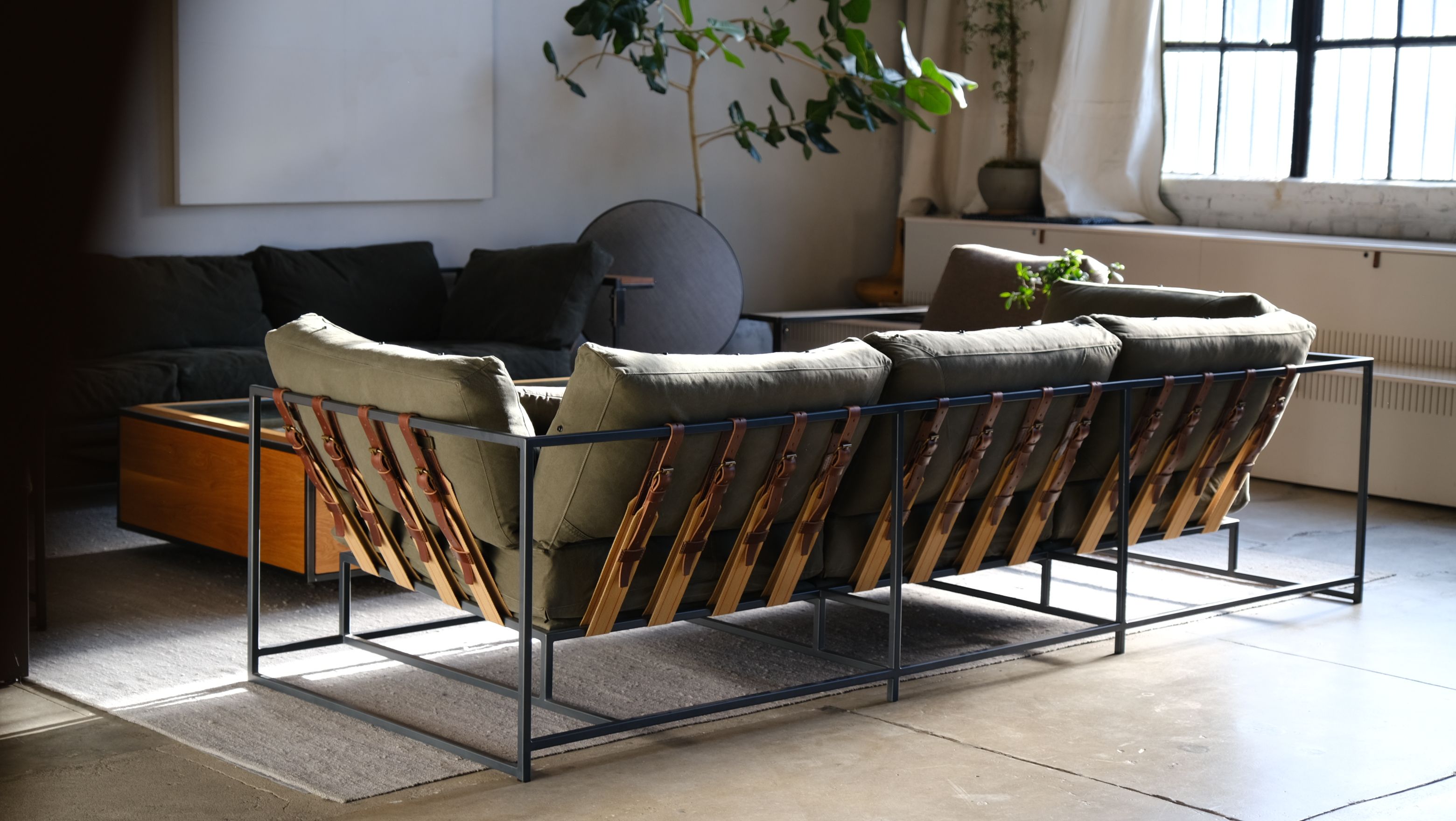 a couch is sitting on a concrete floor in a living room next to a window .