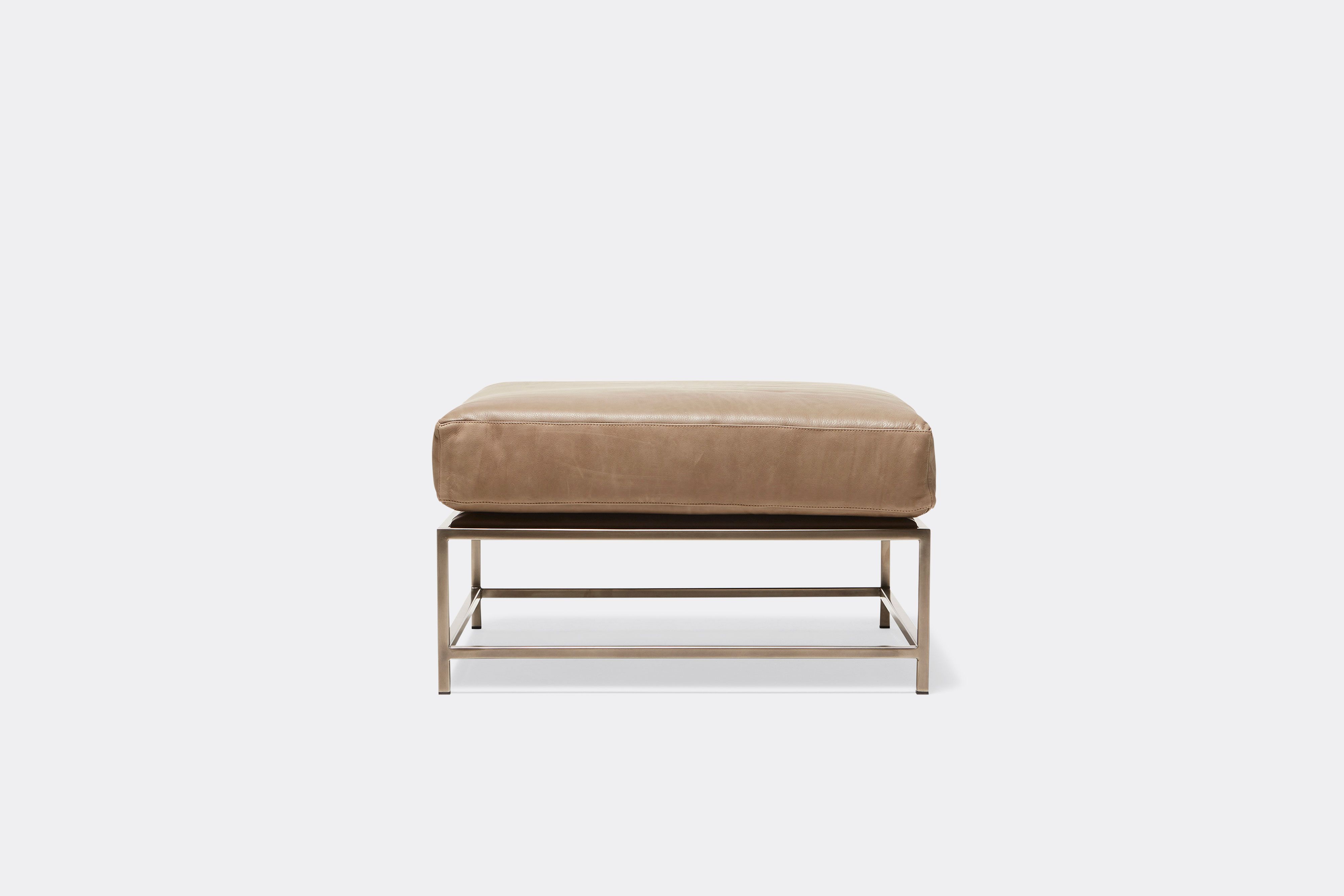 front of ottoman with tan leather upholstery on antique nickel metal frame