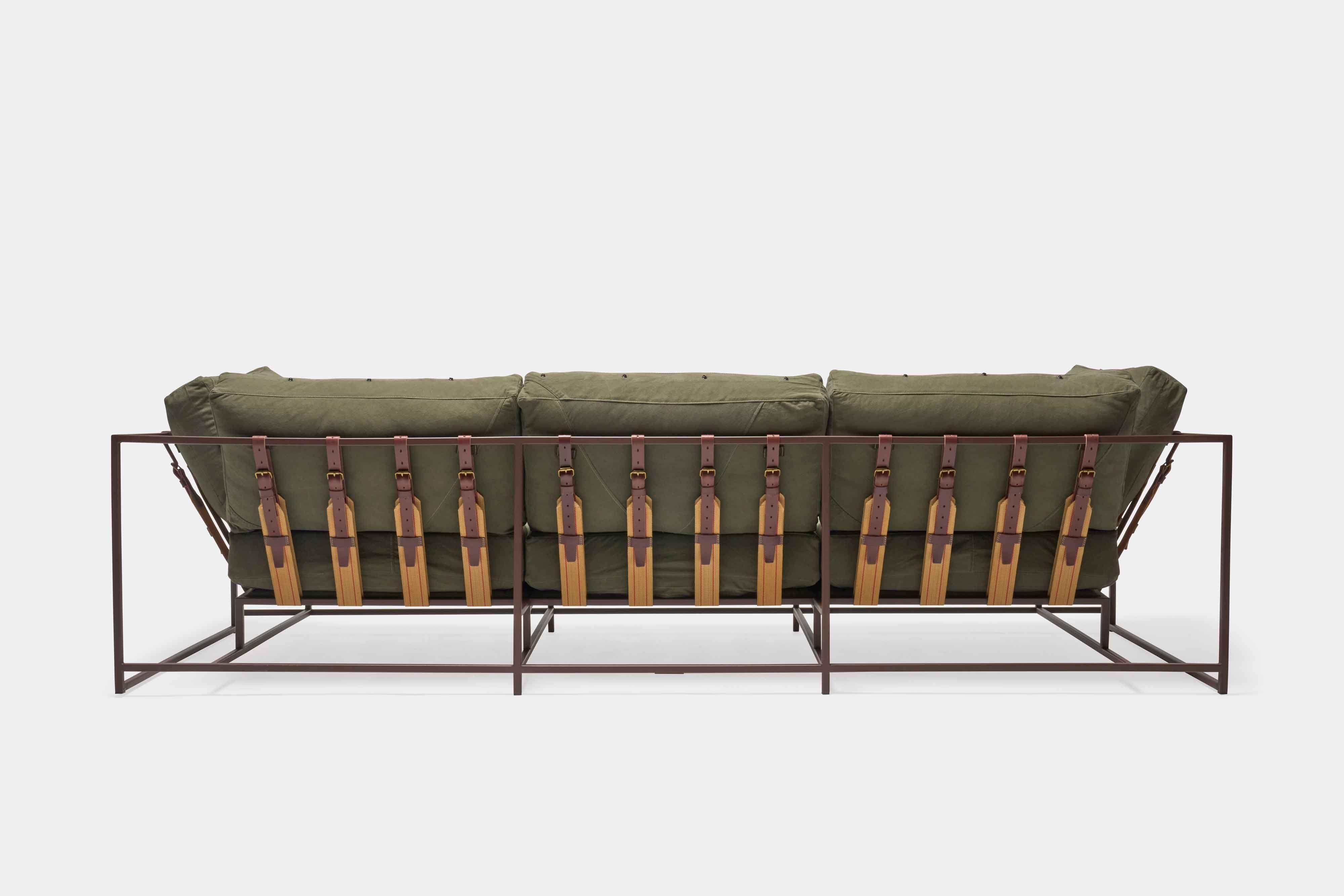 a green couch with a metal frame and leather straps