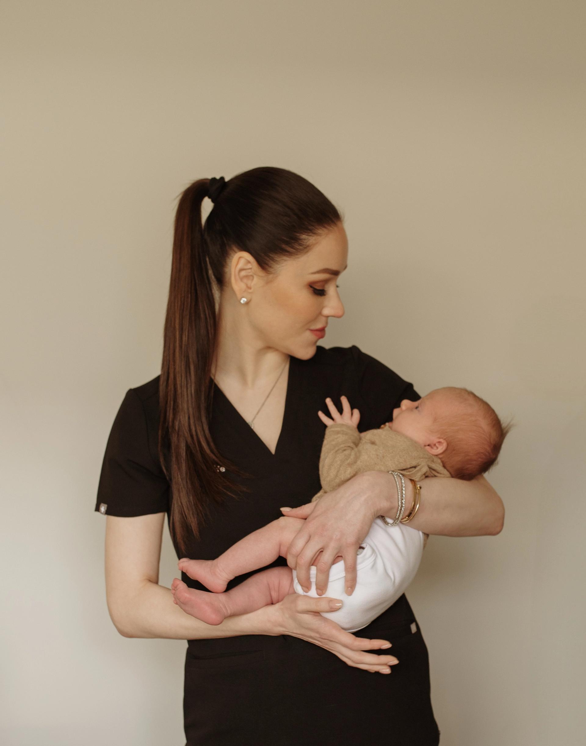 Megan Everett, Nurse Practitioner and Midwife, holding a newborn during an in-home postnatal visit in Perth