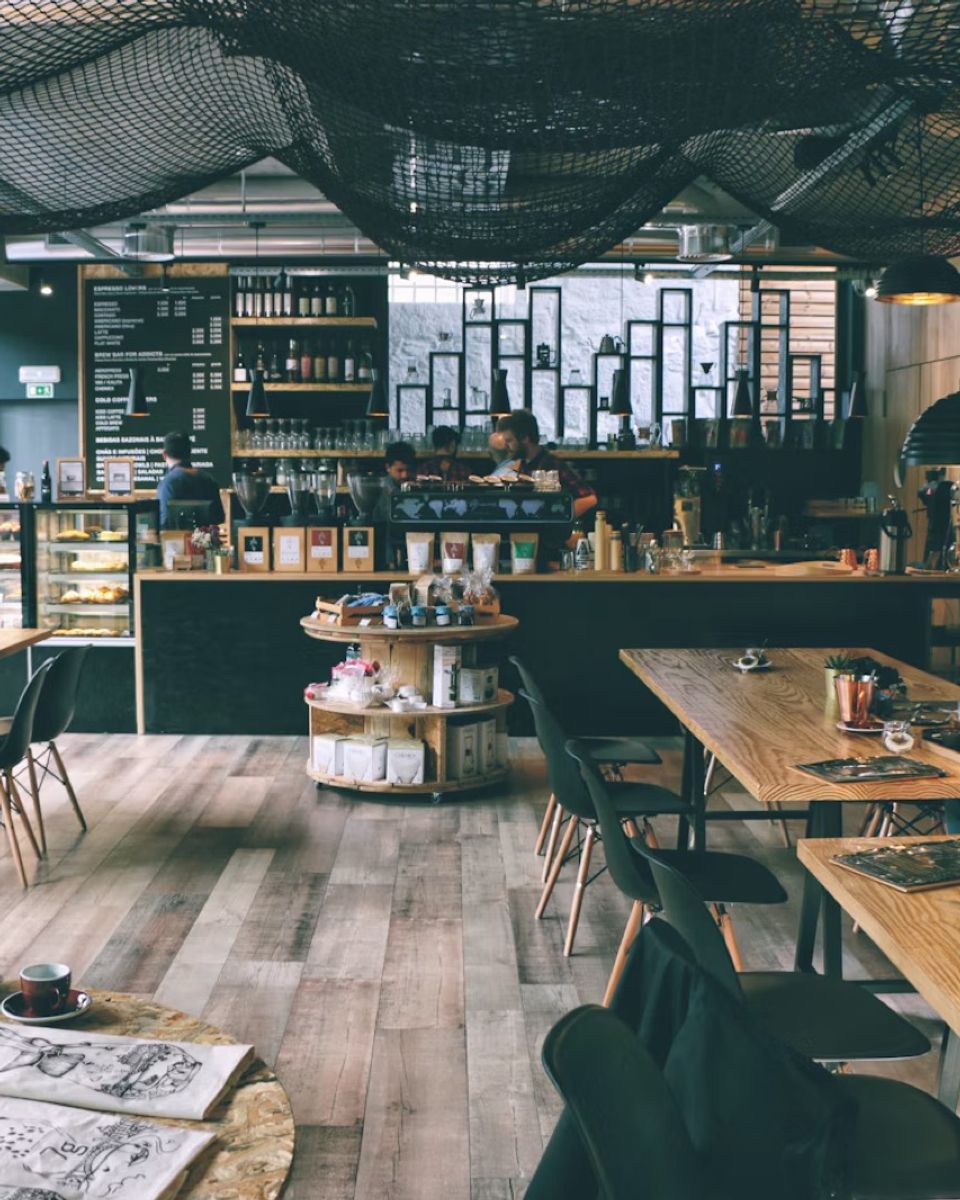 A café with long wooden tables and shelves of jars