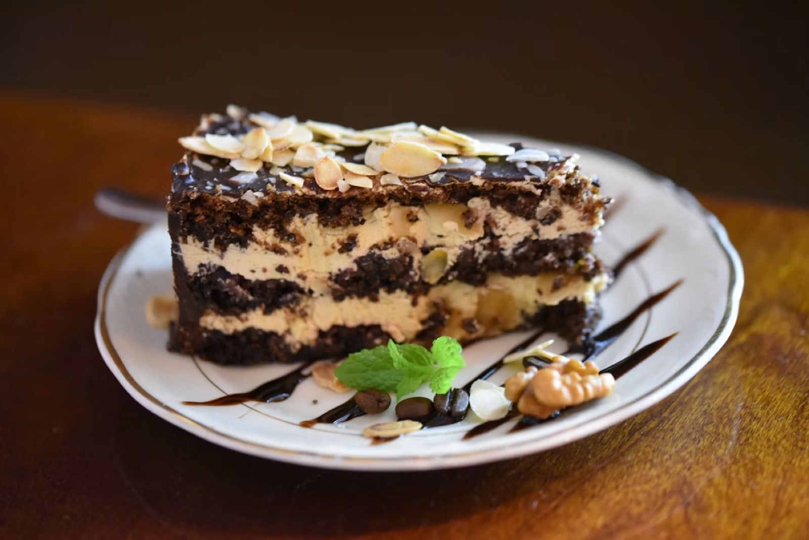 A slice of layered chocolate cake with almonds and fresh mint