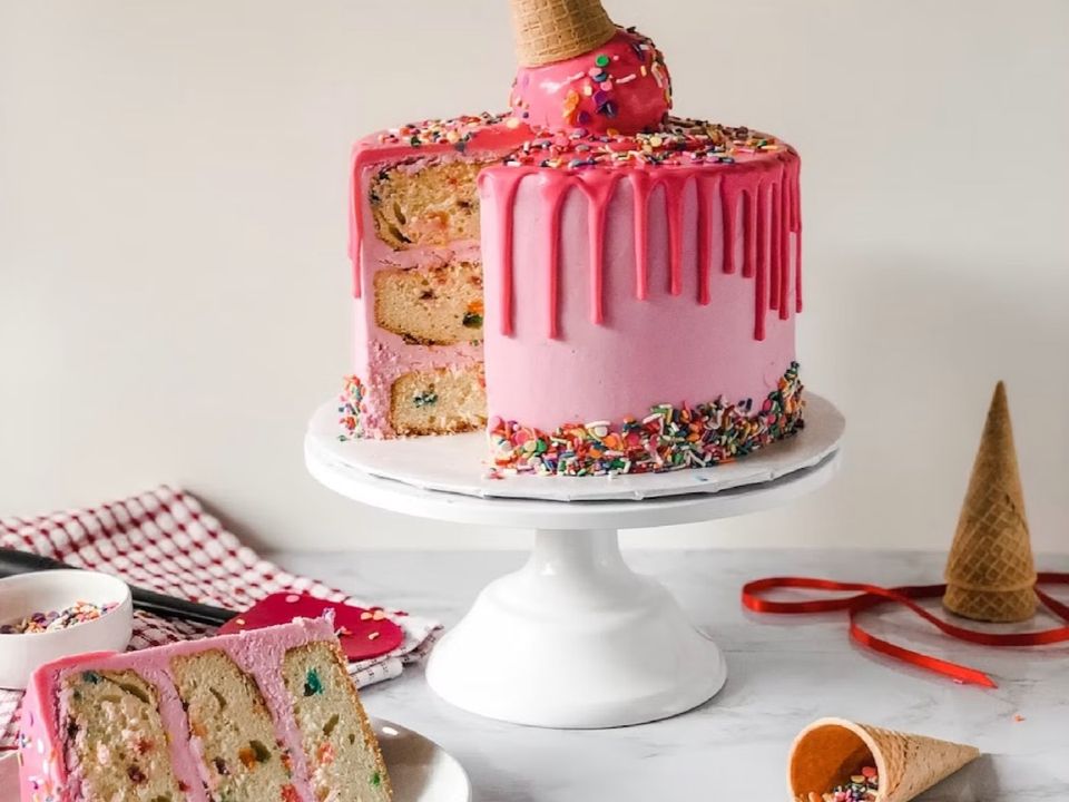 A pink drip cake decorated with sprinkles