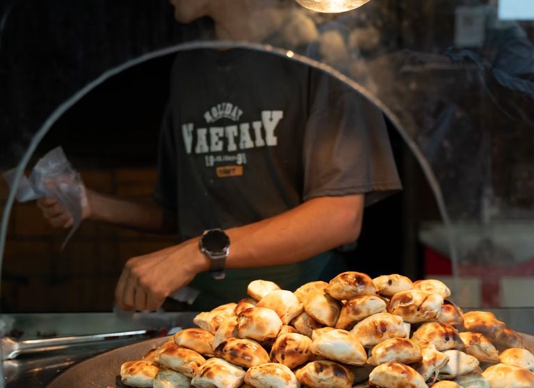 A stallholder serving a tray of golden pastries at a market