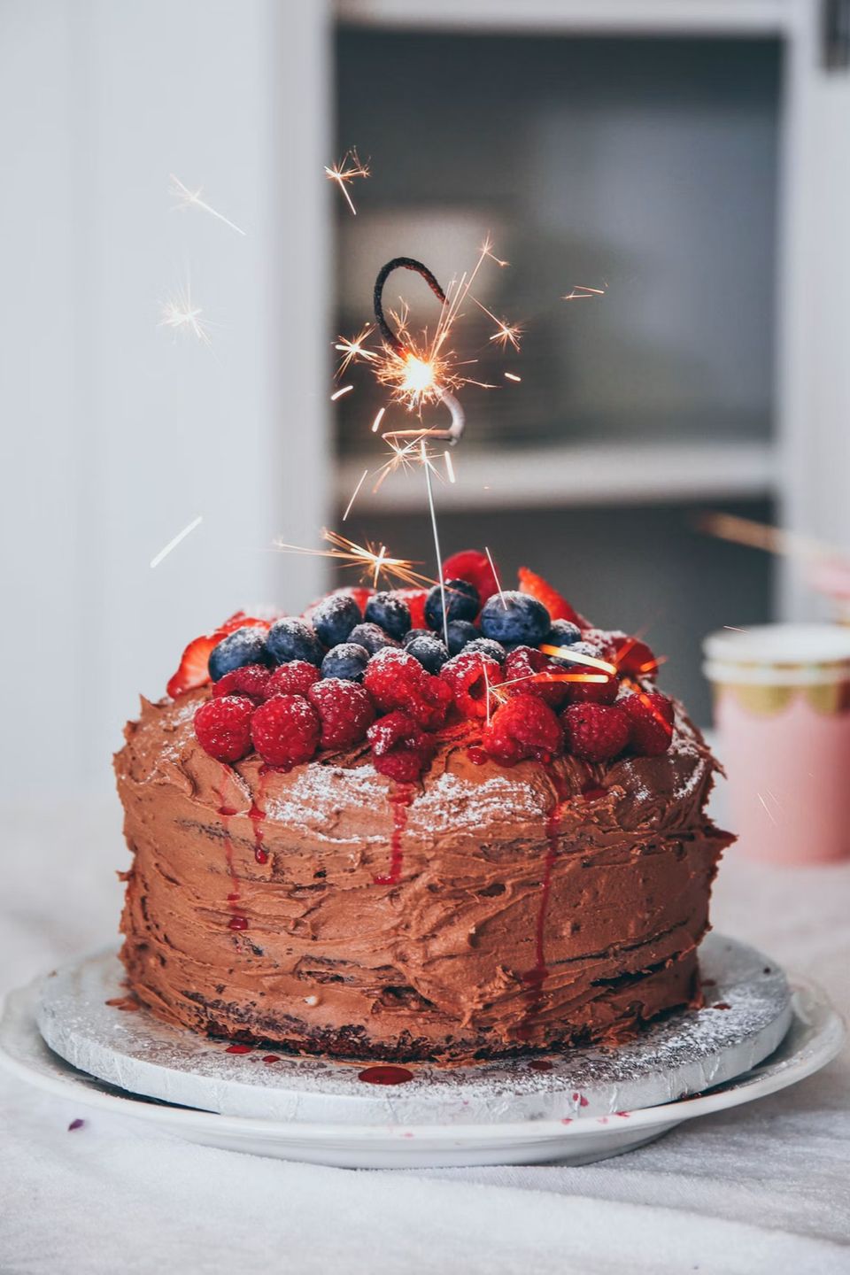 A chocolate celebration cake with berries and a sparkler