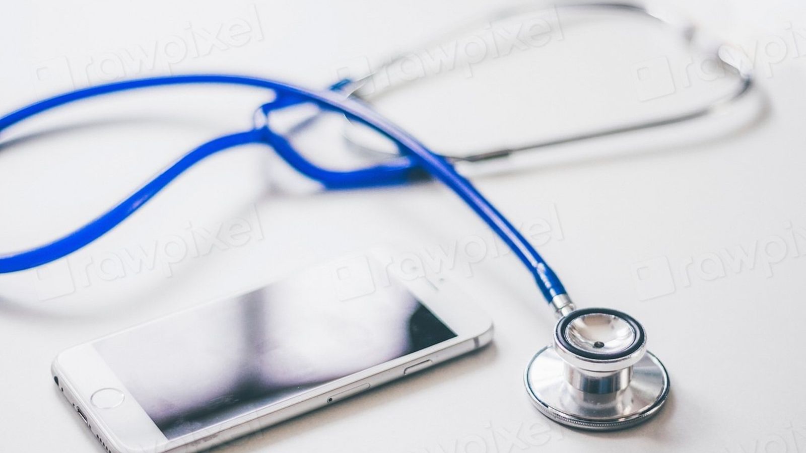 A smartphone next to a blue stethoscope on a white desk