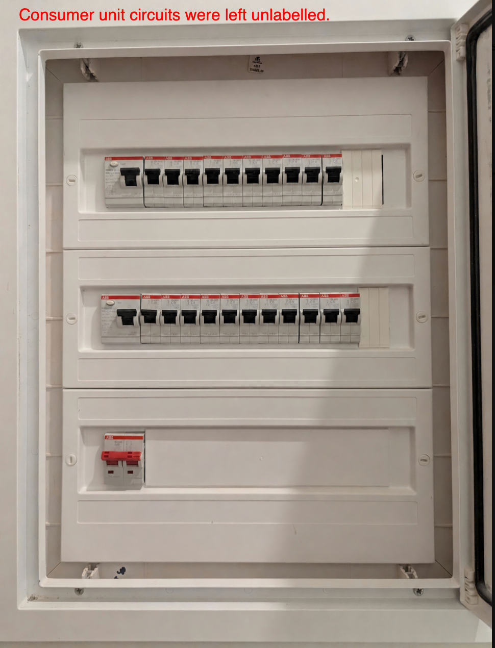 An open consumer unit with rows of circuit breakers, none of them labelled.