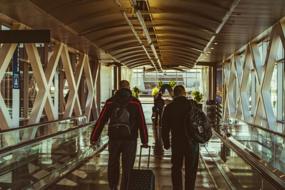 Travellers with backpacks on a moving walkway in an airport