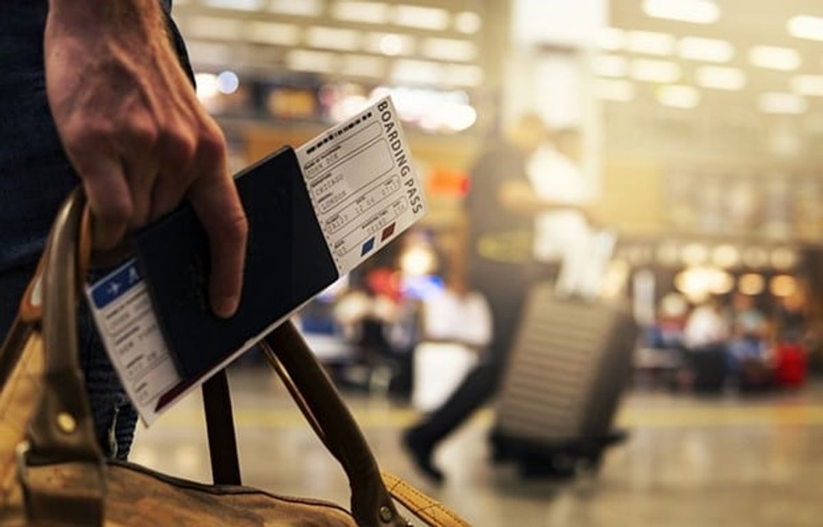 A hand holding a bag and a boarding pass