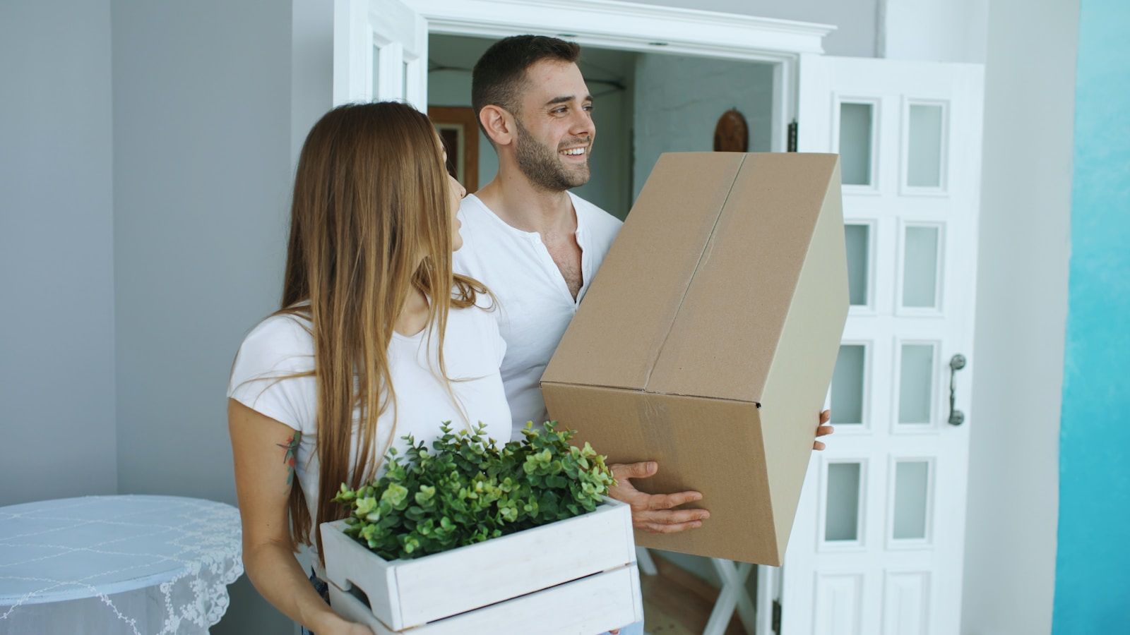 A couple carrying boxes into their new home