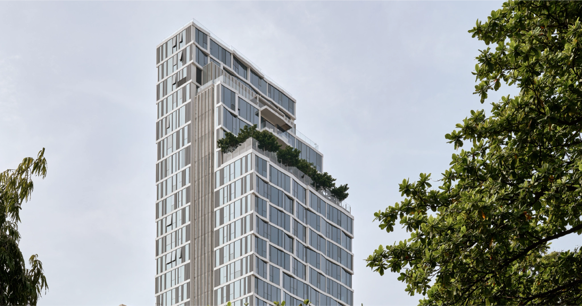 SCOPE Langsuan tower with its glass facade and planted terraces, framed by trees.