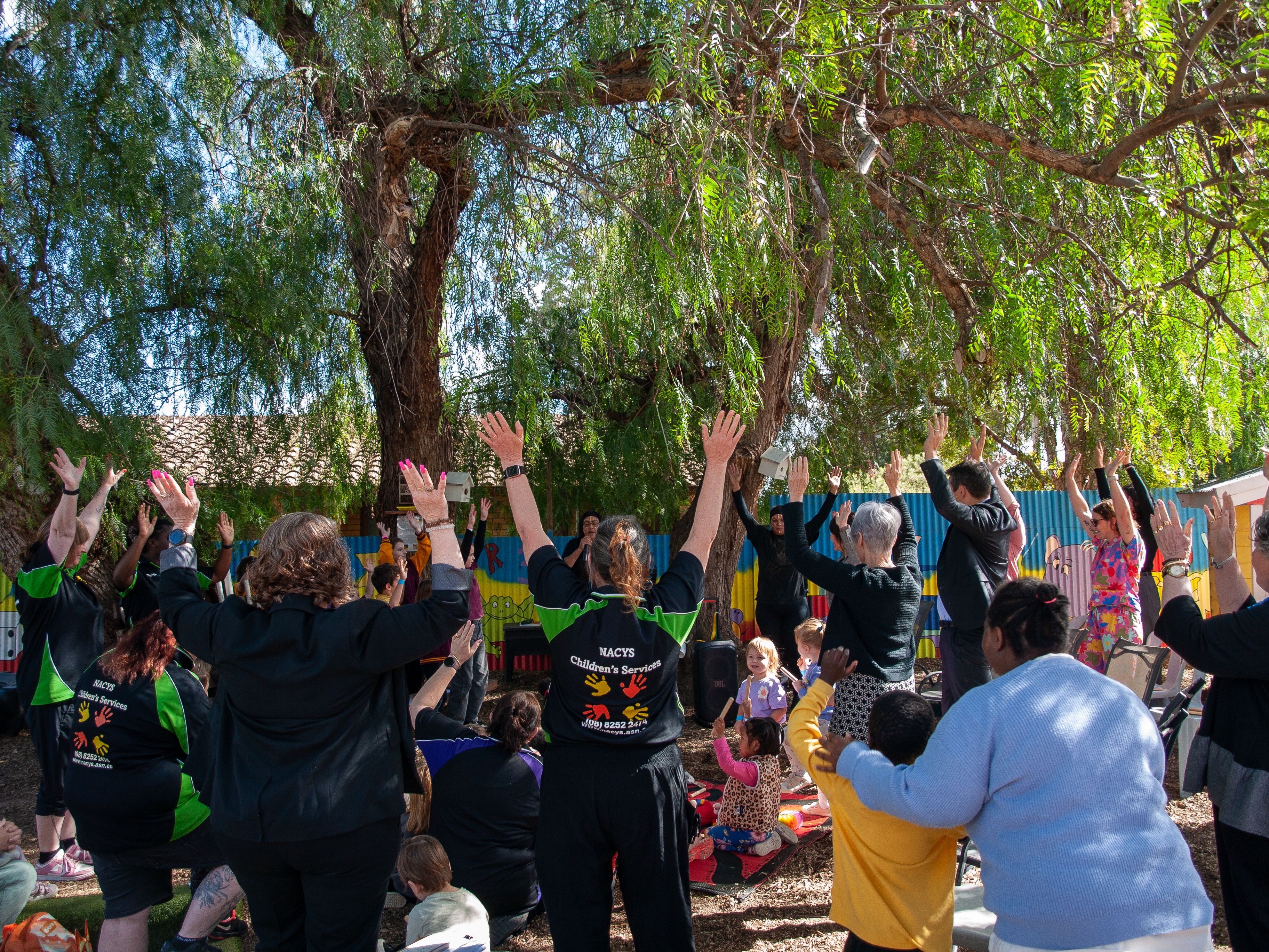Picture of large group of people with NACYS staff their hands are up in the air celebrating. 