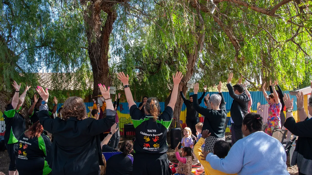Picture of large group of people with NACYS staff their hands are up in the air celebrating.