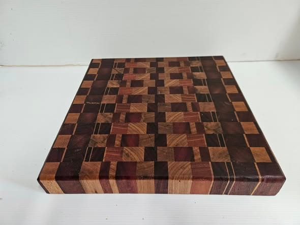 Thick chopping block with a mosaic of dark brown, reddish and golden timber squares