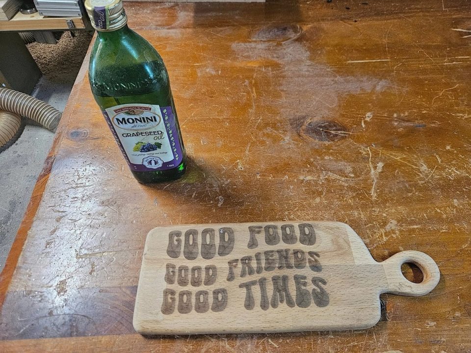 Timber serving board with a round handle hole and engraved Good food, good friends, good times lettering