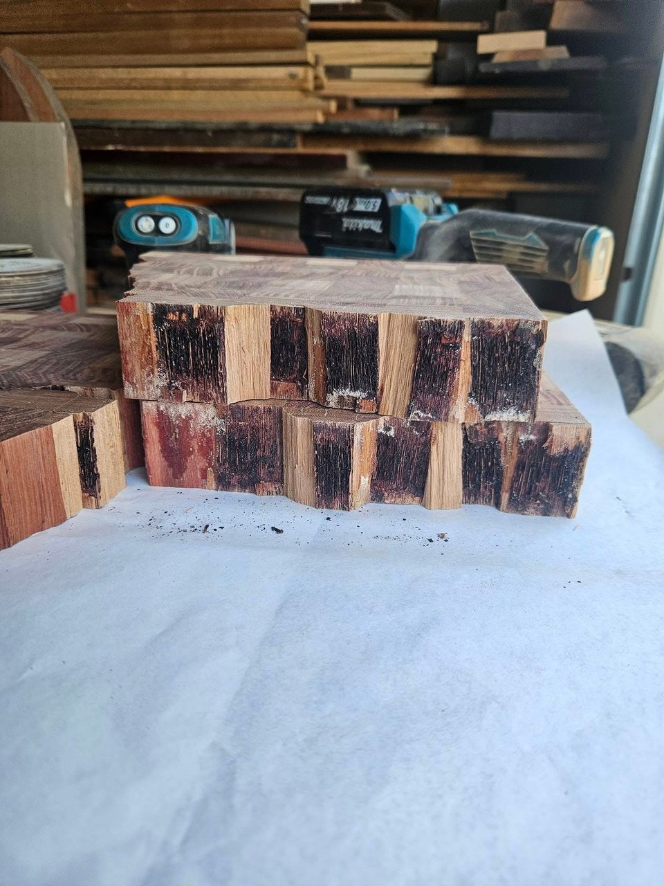 Two thick timber blocks stacked on a workshop surface with alternating dark and light sections