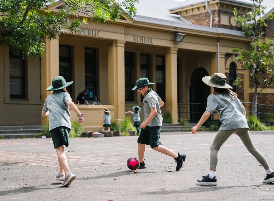 Three children playing soccer outside