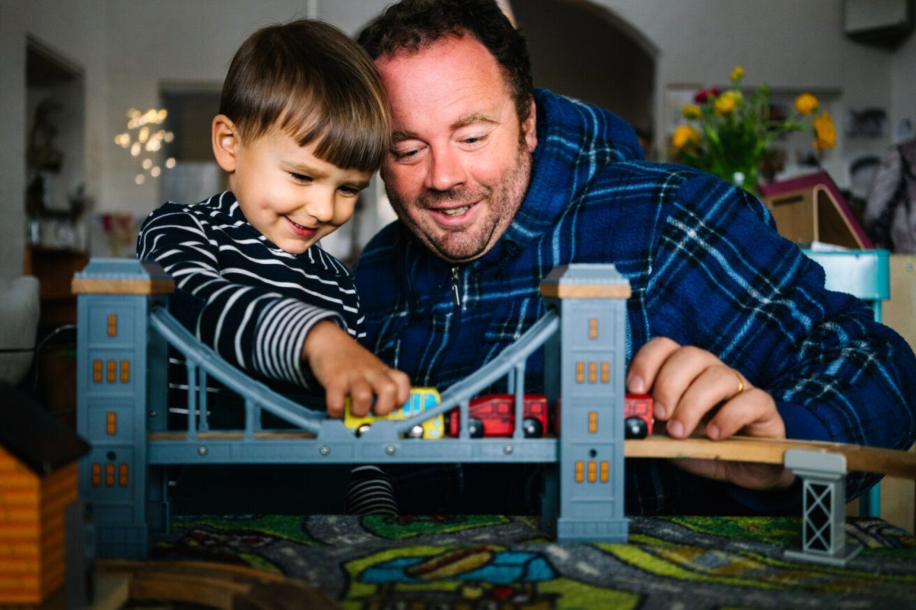 Educator and child playing with toy bridge