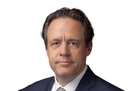 Headshot of a man in a dark suit looking directly at the camera.