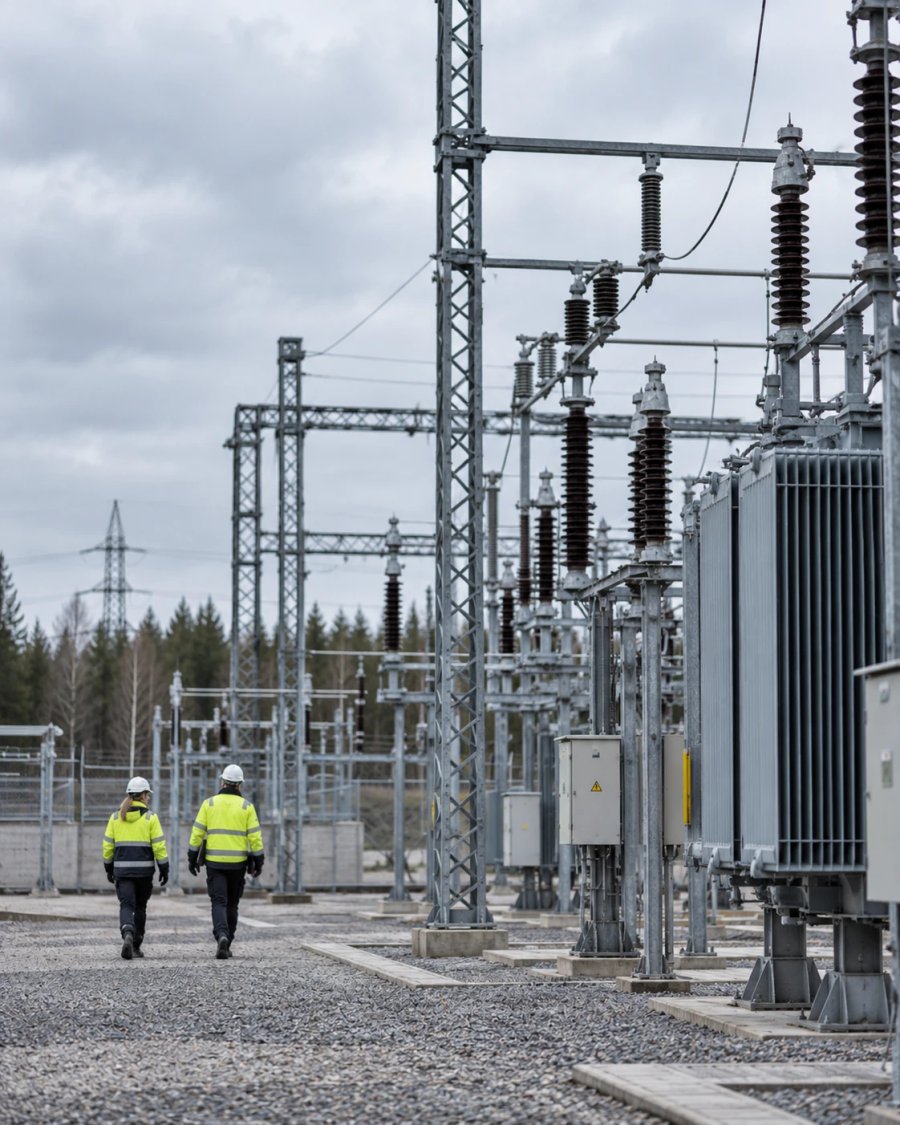 Två personer i varselkläder går genom en elstation